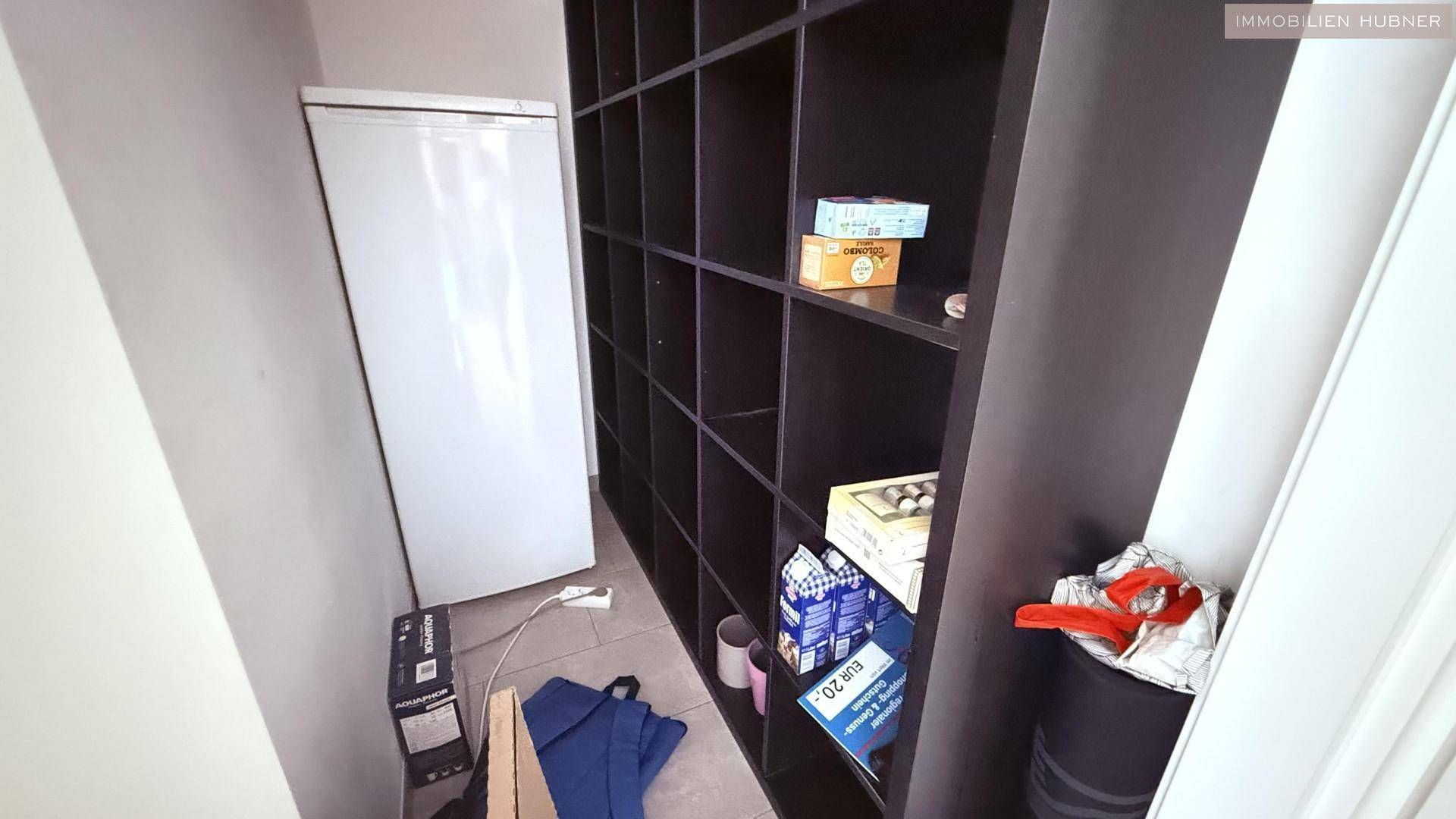 Praktischer Abstellraum mit Regal und Kühlschrank für zusätzlichen Stauraum.