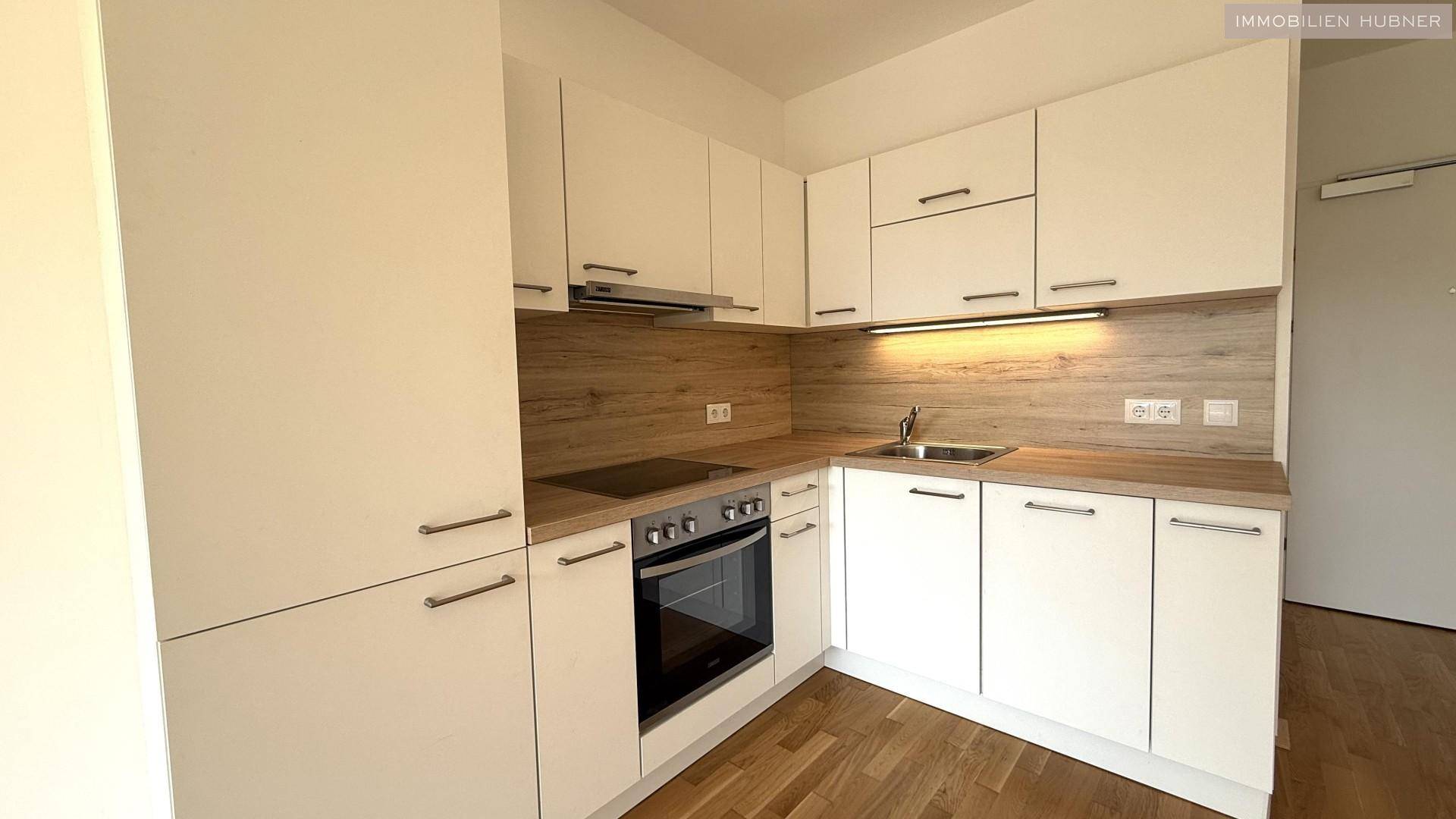 Moderne Einbauküche mit weißen Fronten, Holz-Arbeitsplatte und integrierten Geräten.