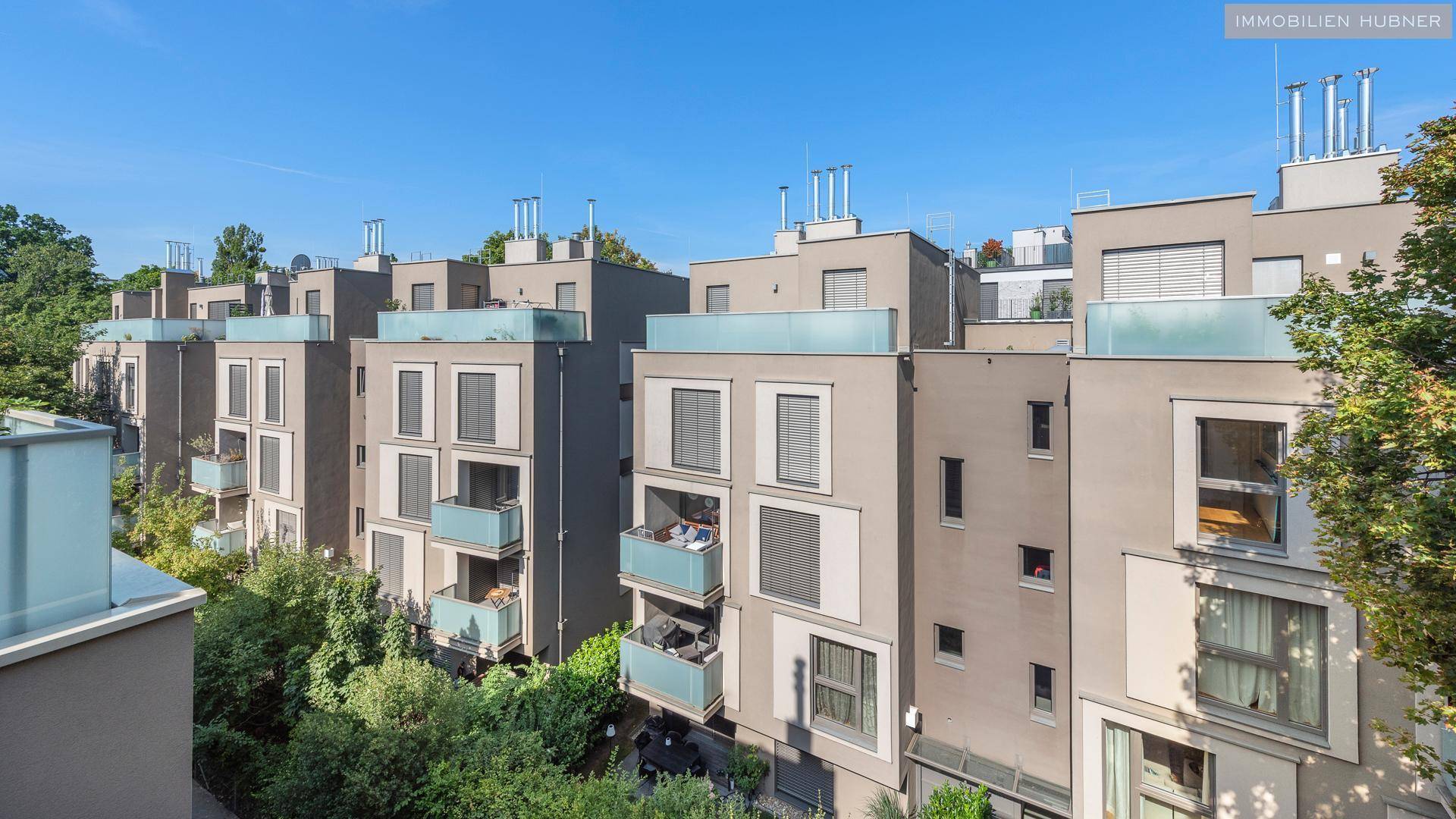 Moderne Wohngebäude mit Balkonen und großen Fenstern in einer grünen Umgebung.