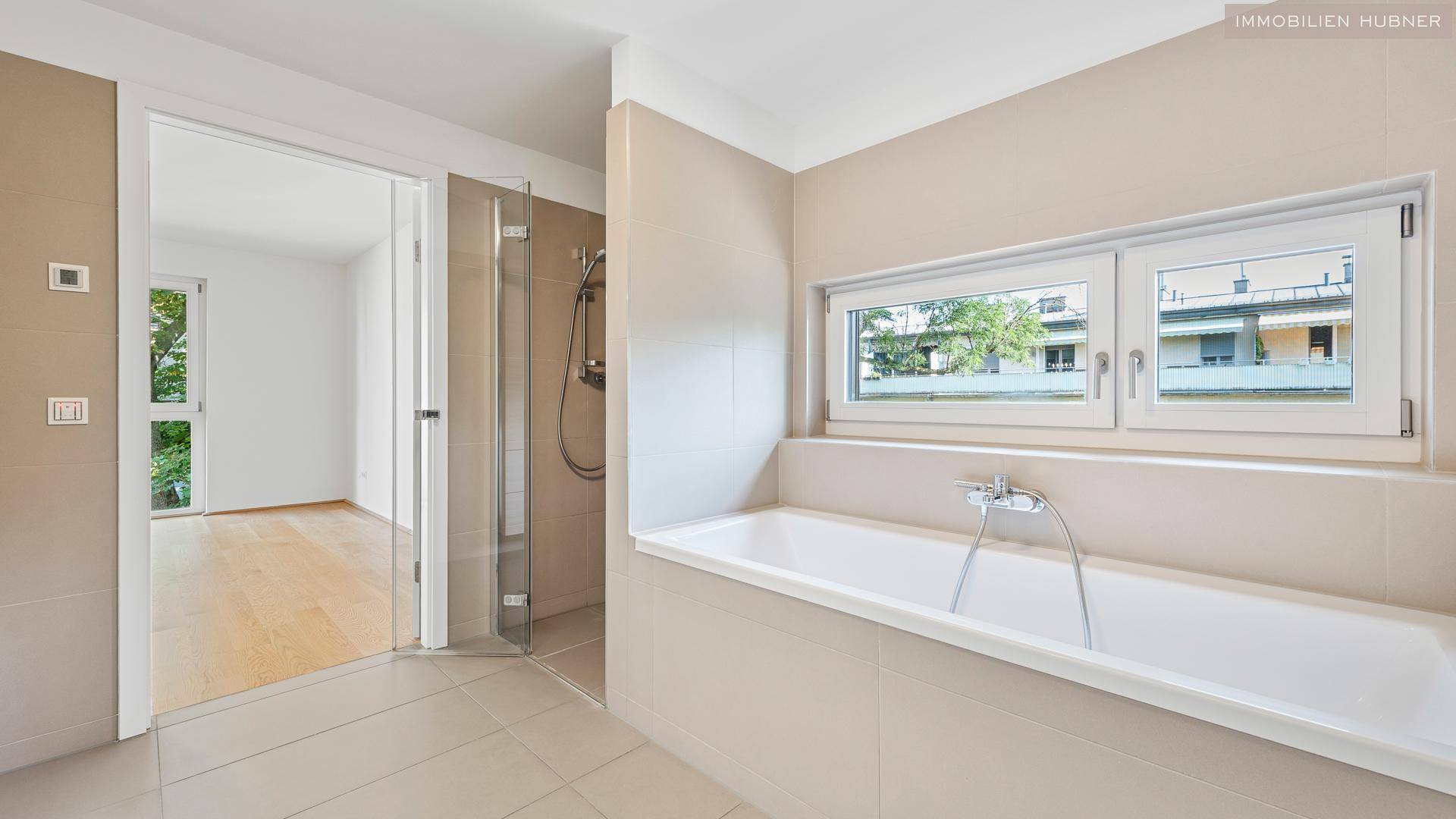 Helles Badezimmer mit Badewanne, Dusche und Fenster für natürliche Belüftung.