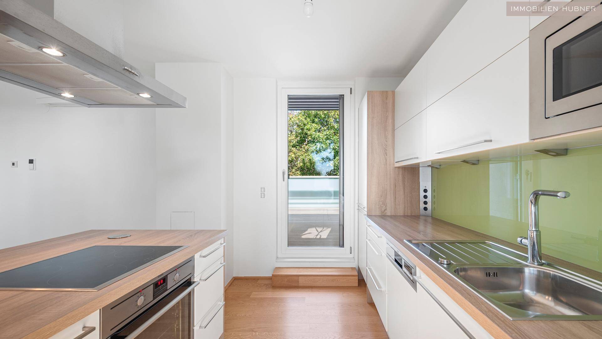 Moderne Küche mit Induktionskochfeld, Backofen und Zugang zur Terrasse.
