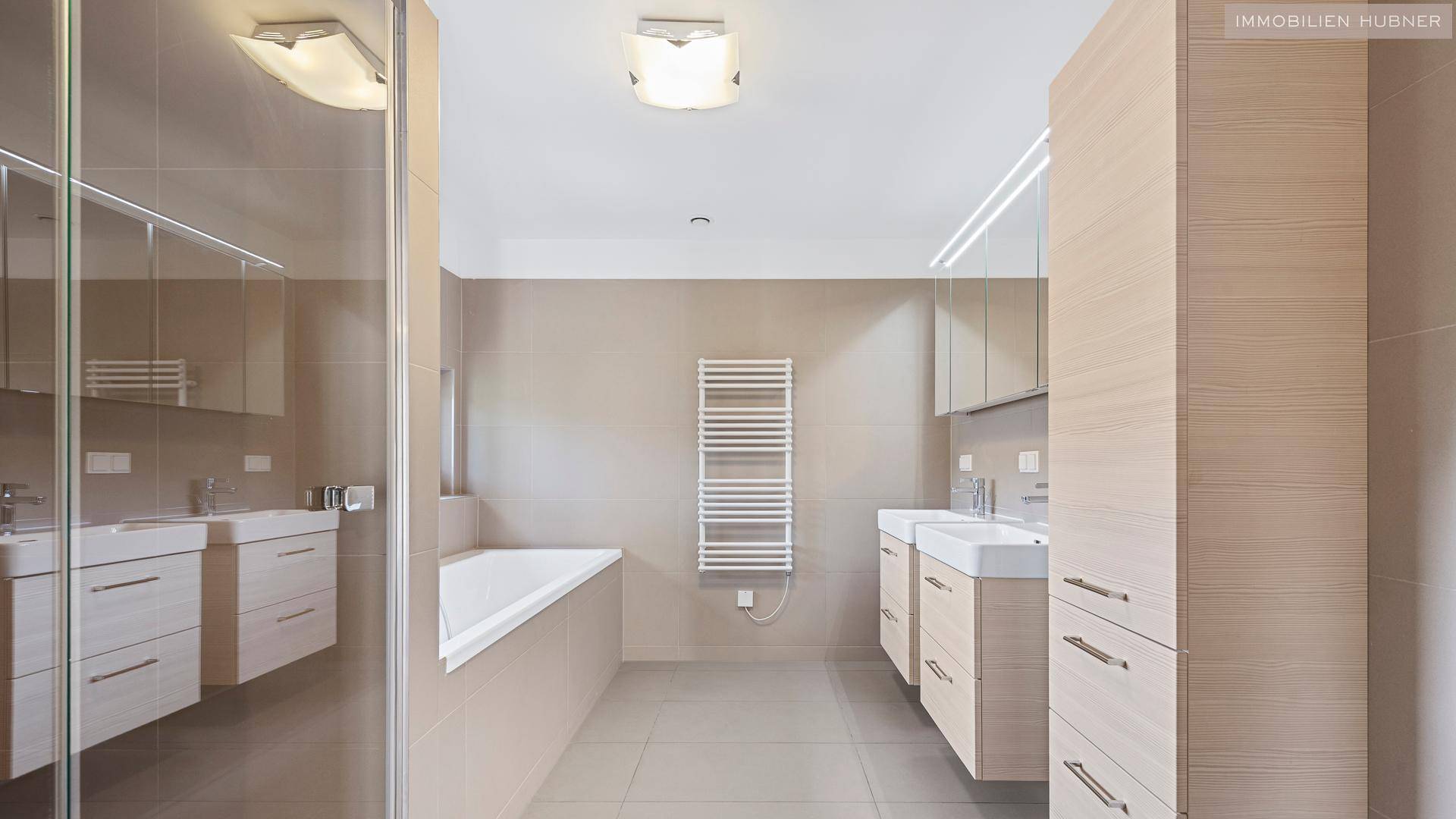 Modernes Badezimmer mit Badewanne, Dusche, Doppelwaschbecken und Handtuchheizung.