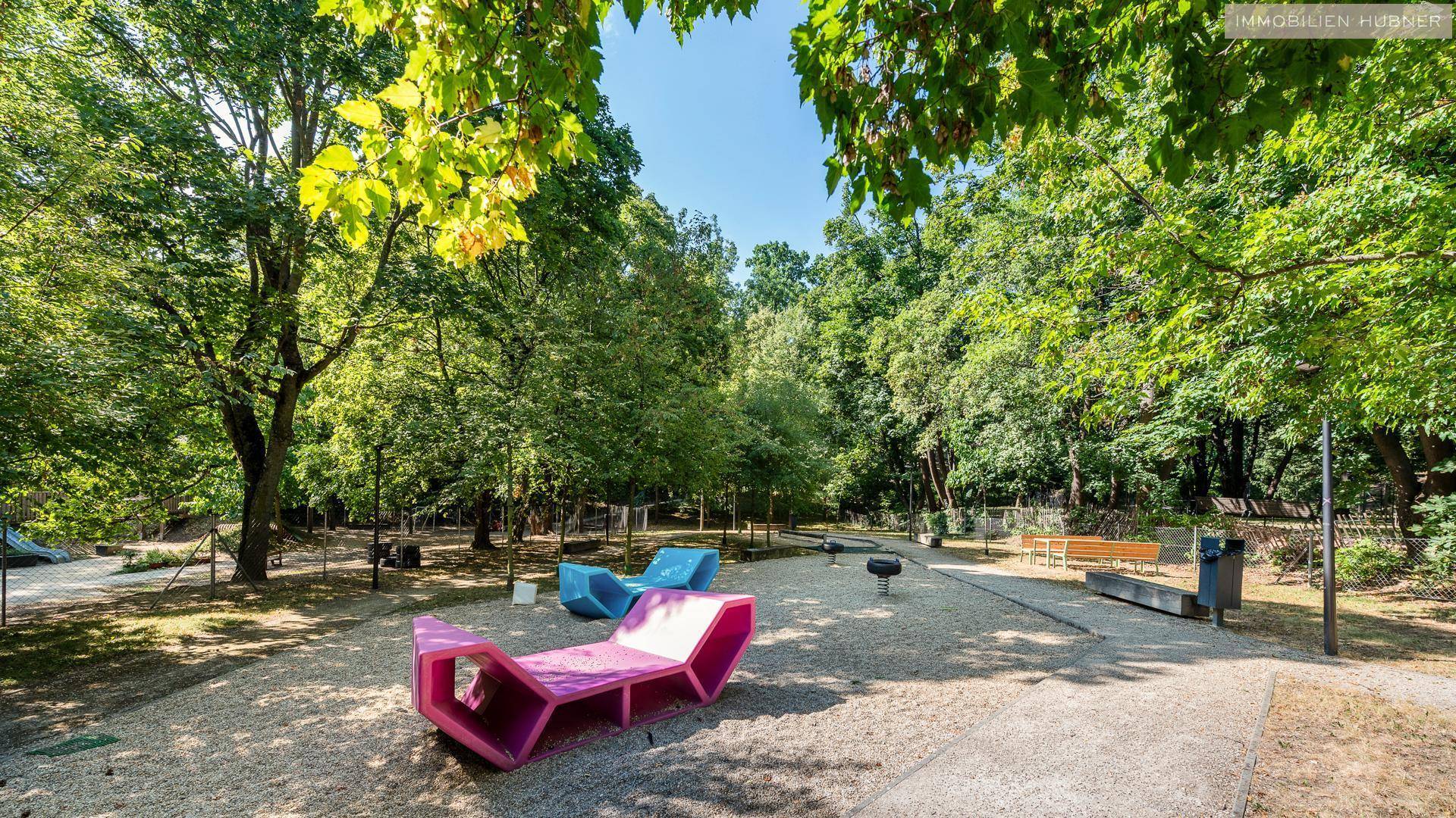 Moderner Spielplatz mit bunten Spielgeräten und viel Grün in der Umgebung.