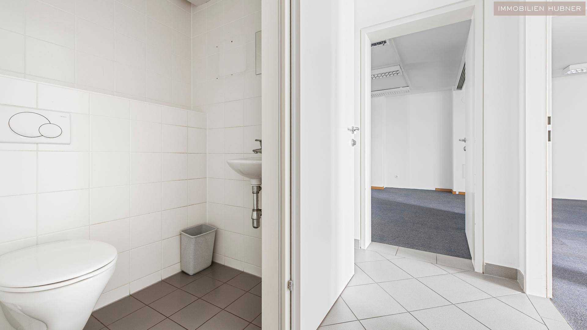 Separate Toilette mit Waschbecken und Fliesenboden, die funktional und sauber ist.