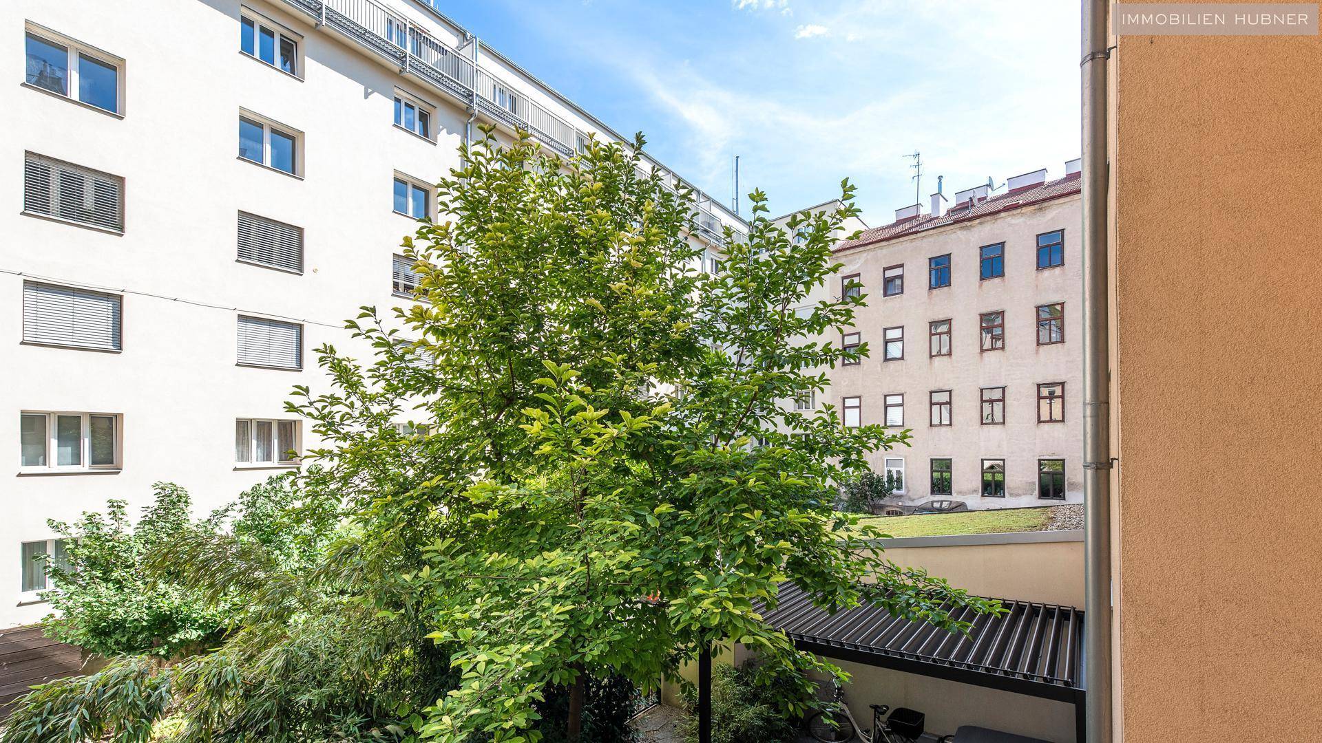 Blick von einem Balkon auf einen grünen Innenhof und die Fassaden der umliegenden Wohngebäude.