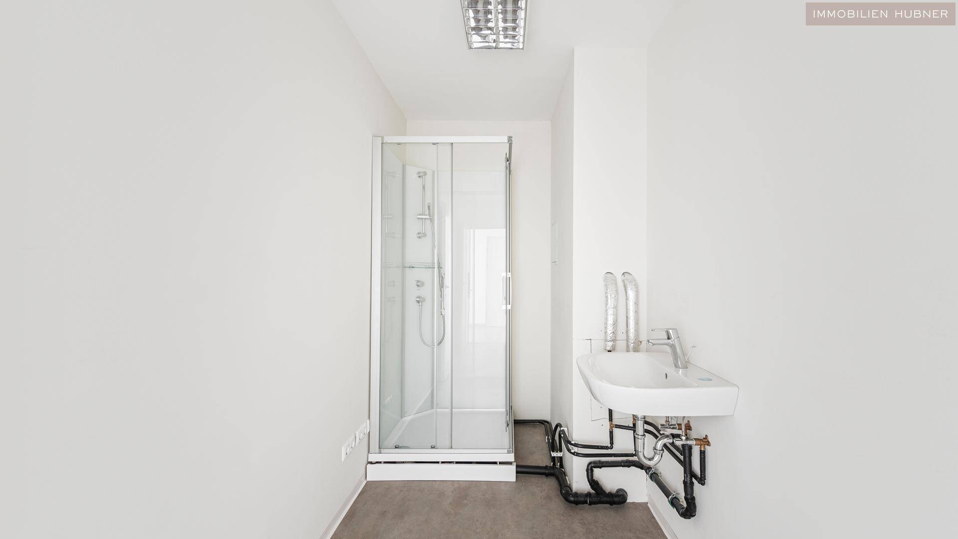 Einfaches Badezimmer mit Duschkabine und Waschbecken, ideal für den täglichen Gebrauch.