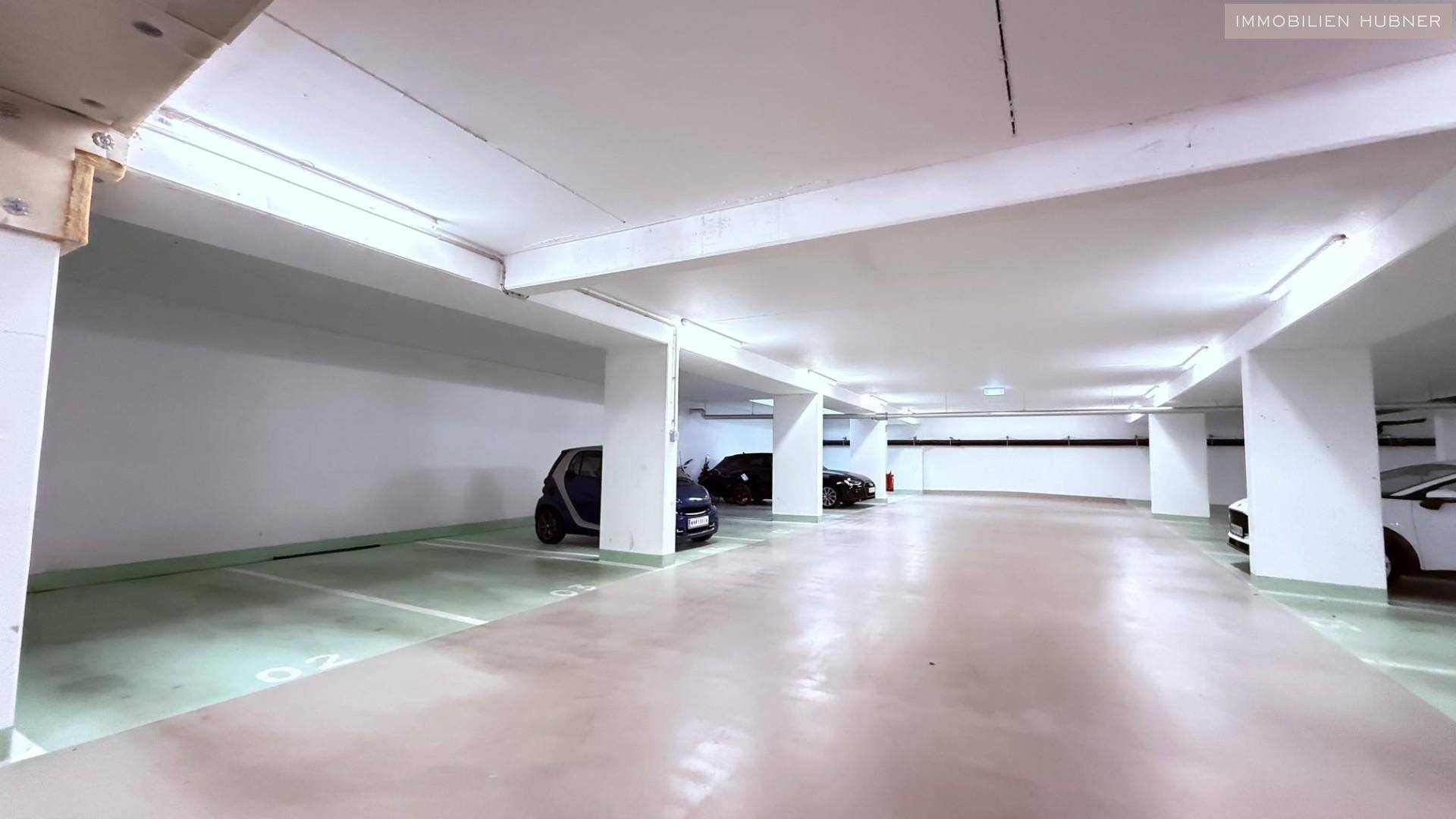 Geräumige Tiefgarage mit mehreren Stellplätzen und heller Beleuchtung.