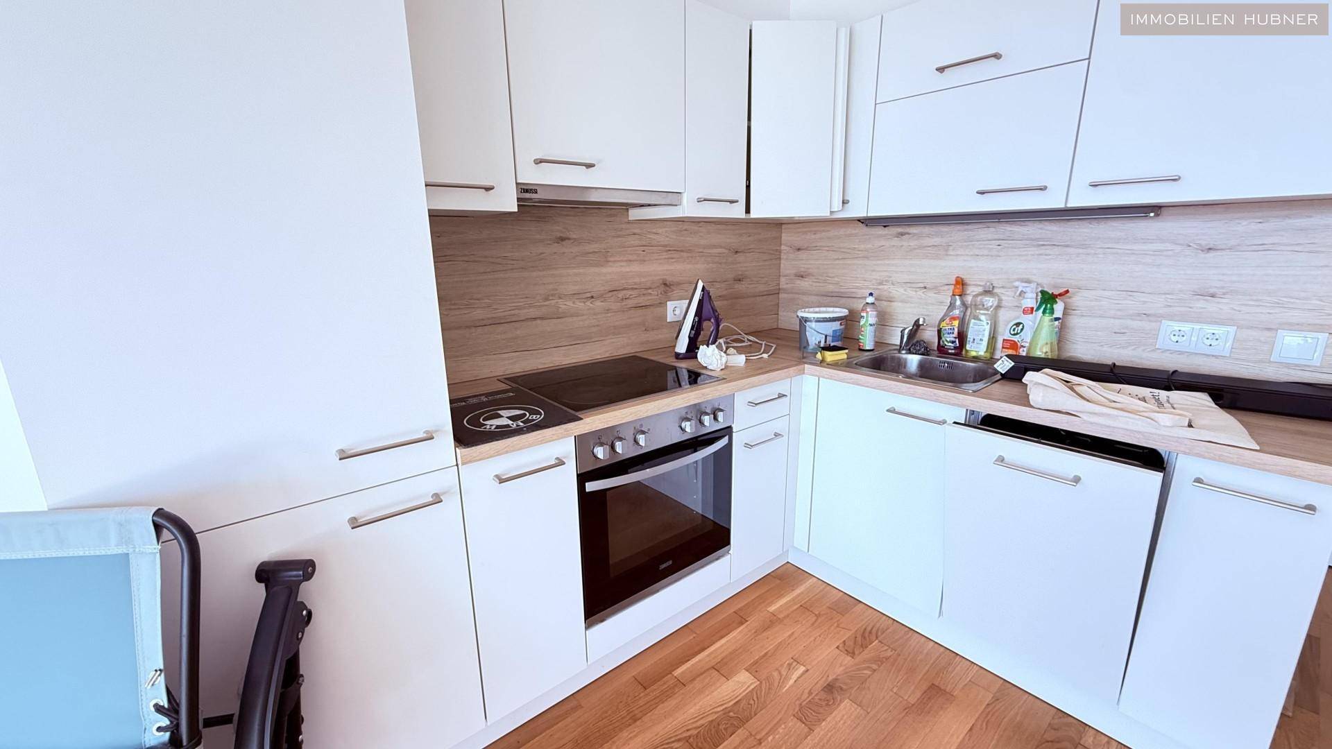 Moderne Einbauküche mit weißen Schränken, Holzoptik-Arbeitsplatte und integrierten Geräten.