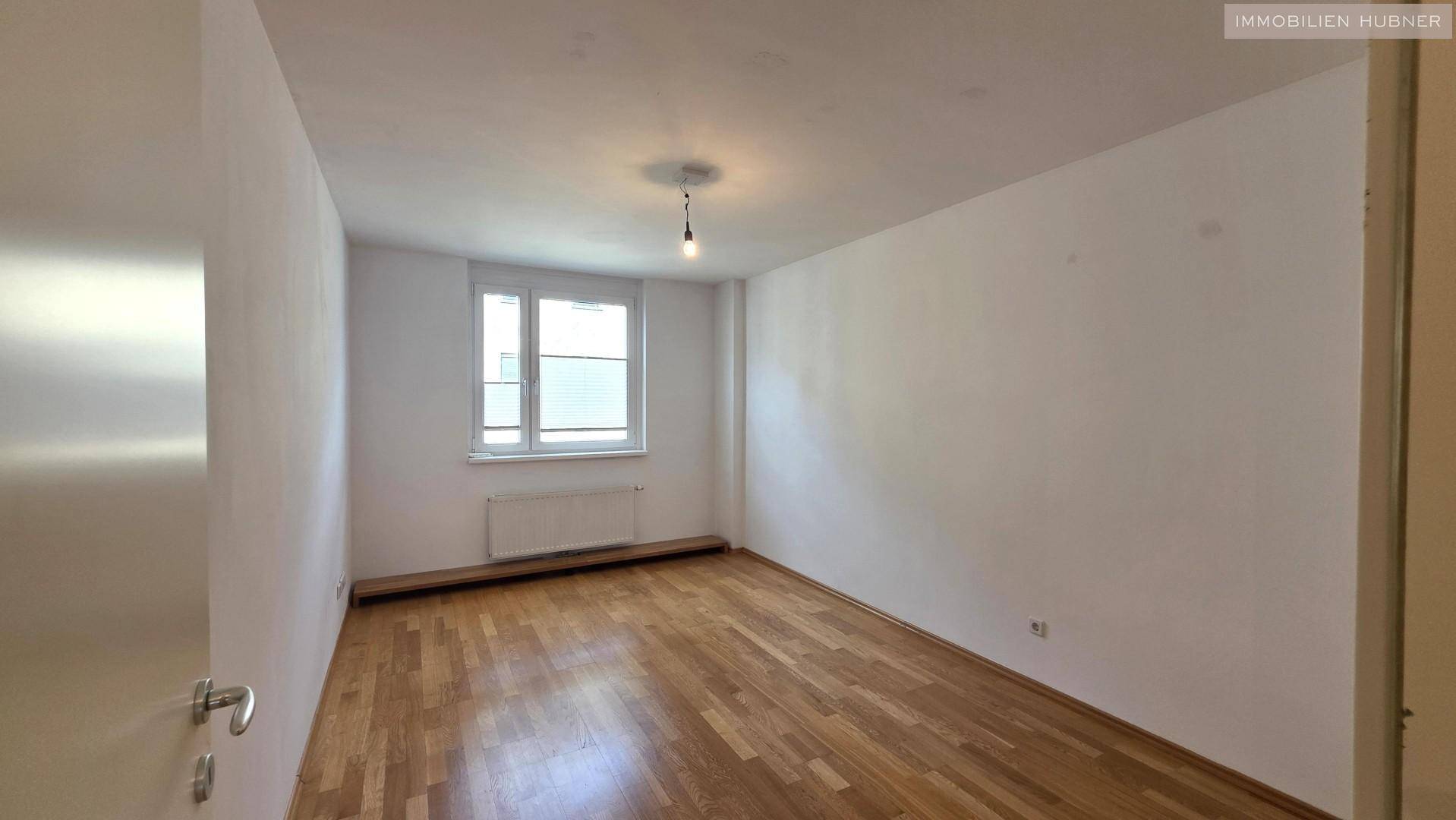 Geräumiges Zimmer mit Parkettboden und Fenster, bietet vielseitige Nutzungsmöglichkeiten.