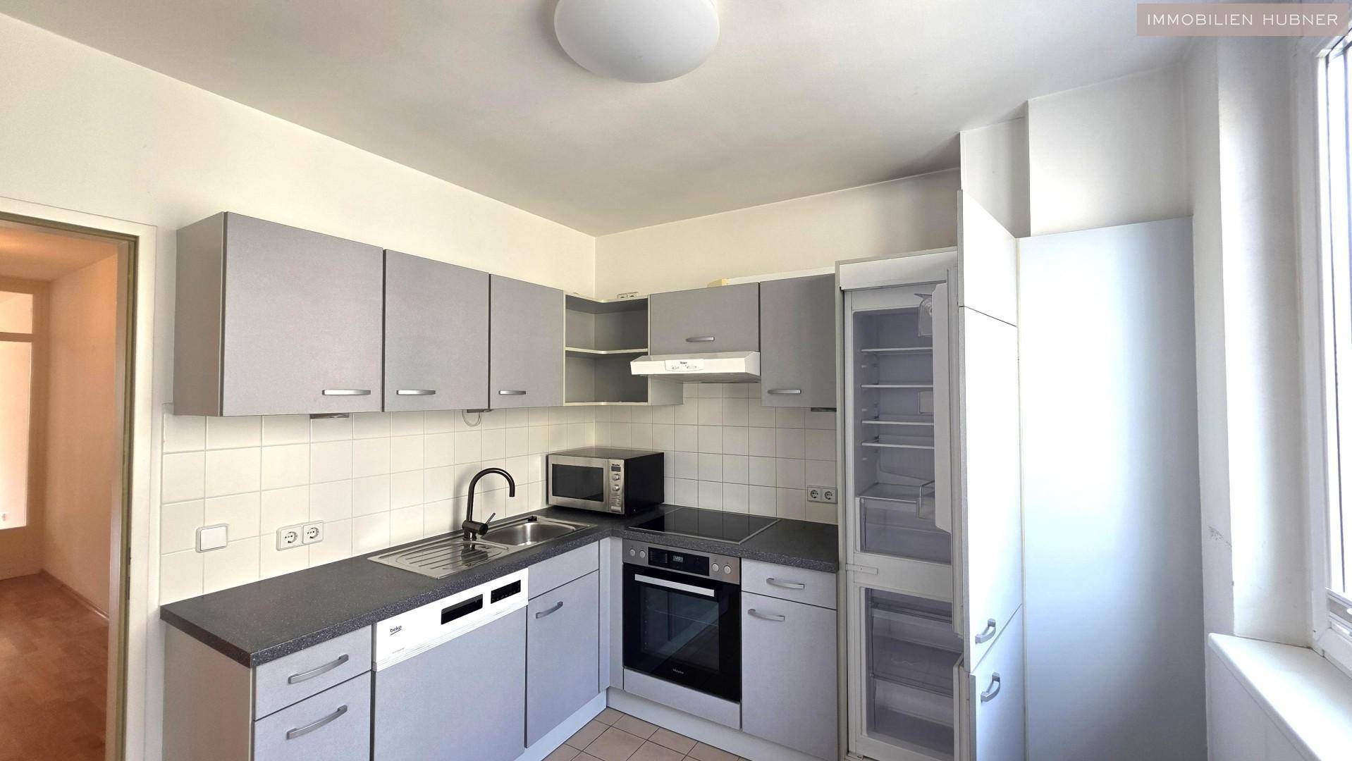 Funktionale Küche mit grauen Schränken, integrierten Geräten und Fliesenboden.