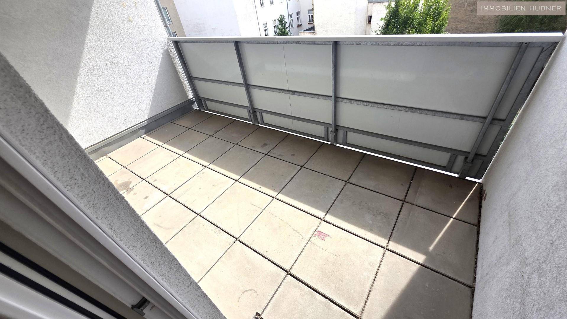 Kleiner Balkon mit Fliesenboden und Blick auf die umliegenden Gebäude.