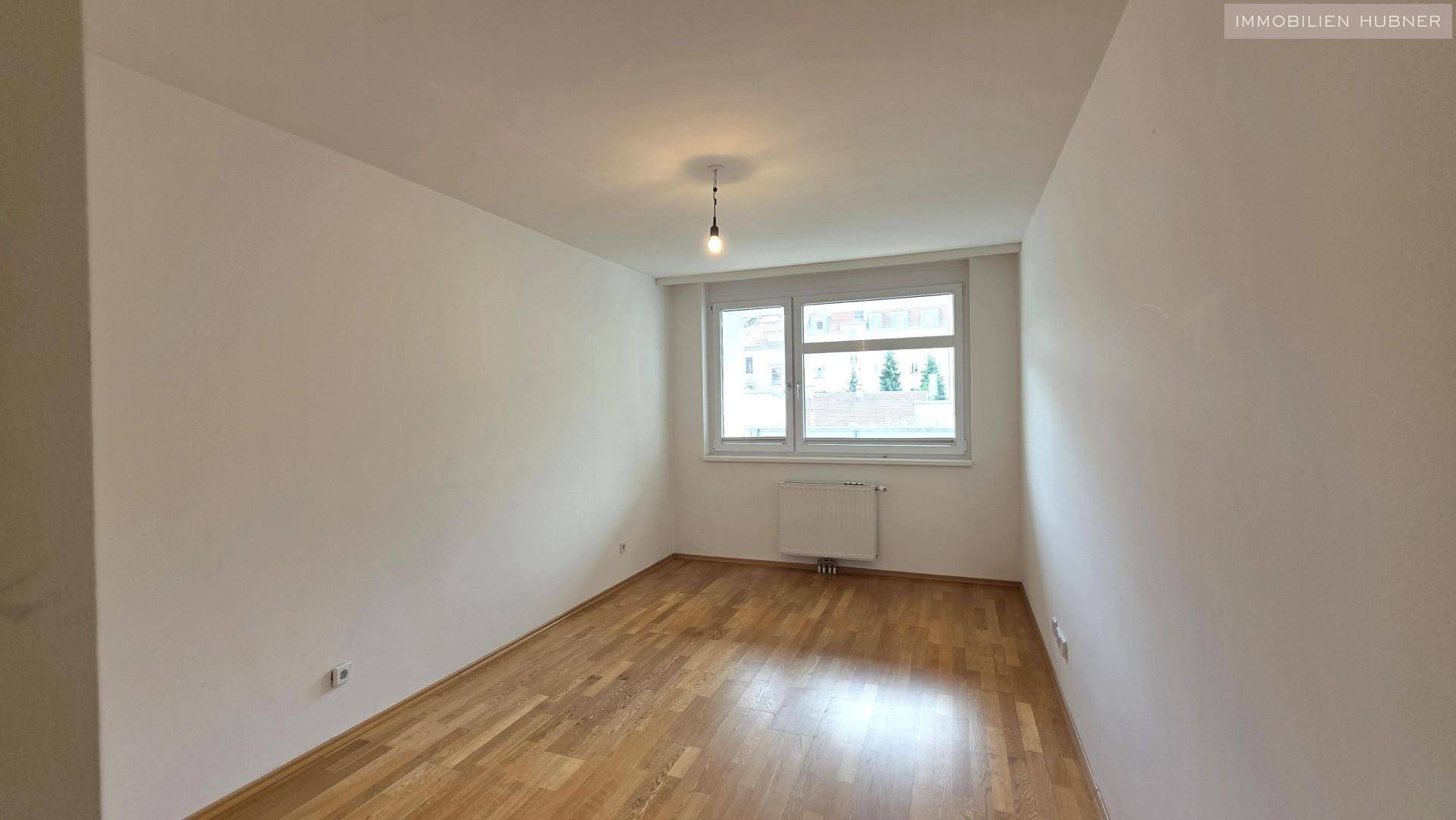 Freundliches Zimmer mit Parkettboden und Fenster, gut beleuchtet und gepflegt.