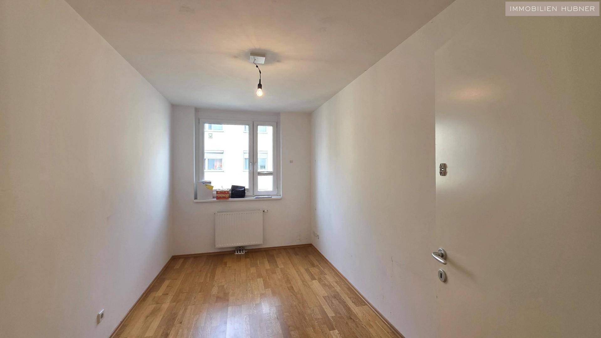Helles Zimmer mit Parkettboden und Fenster, ideal als Schlaf- oder Arbeitszimmer.