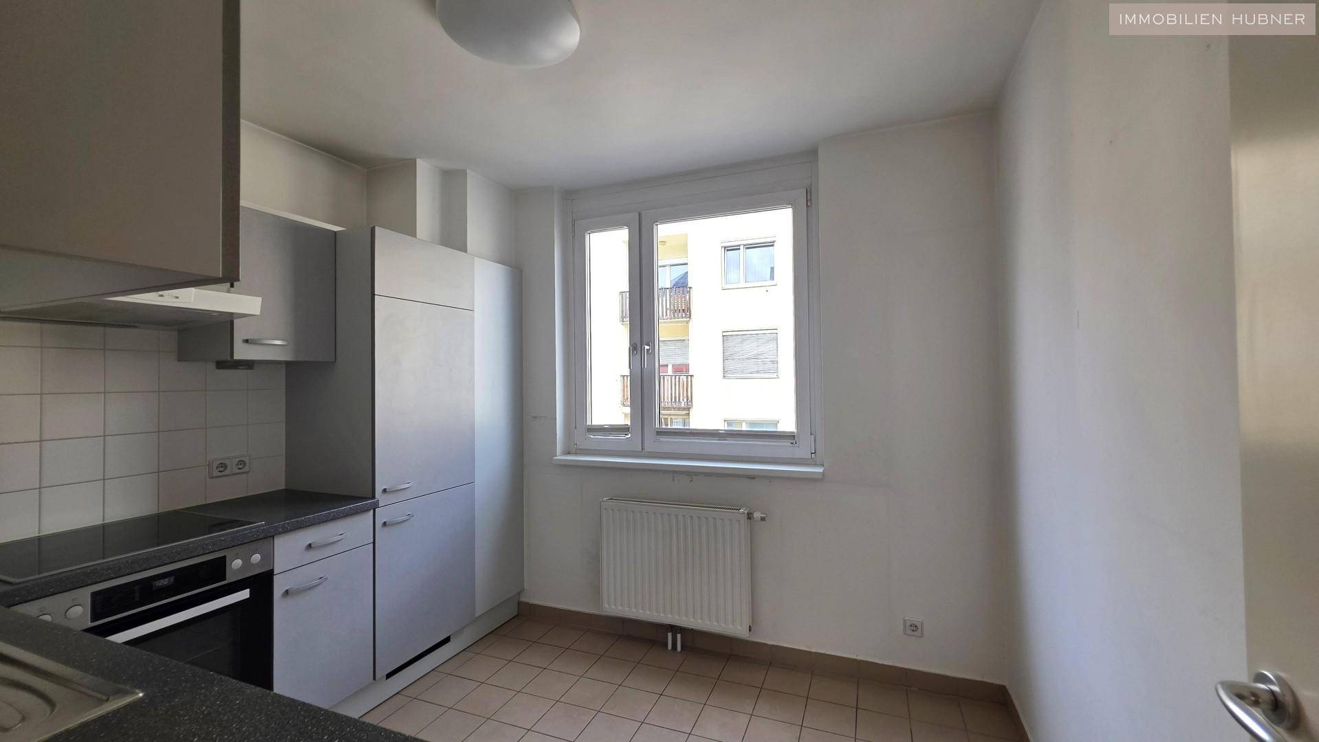 Küchenbereich mit Fenster, Heizkörper und Fliesenboden, bereit für die Einrichtung.