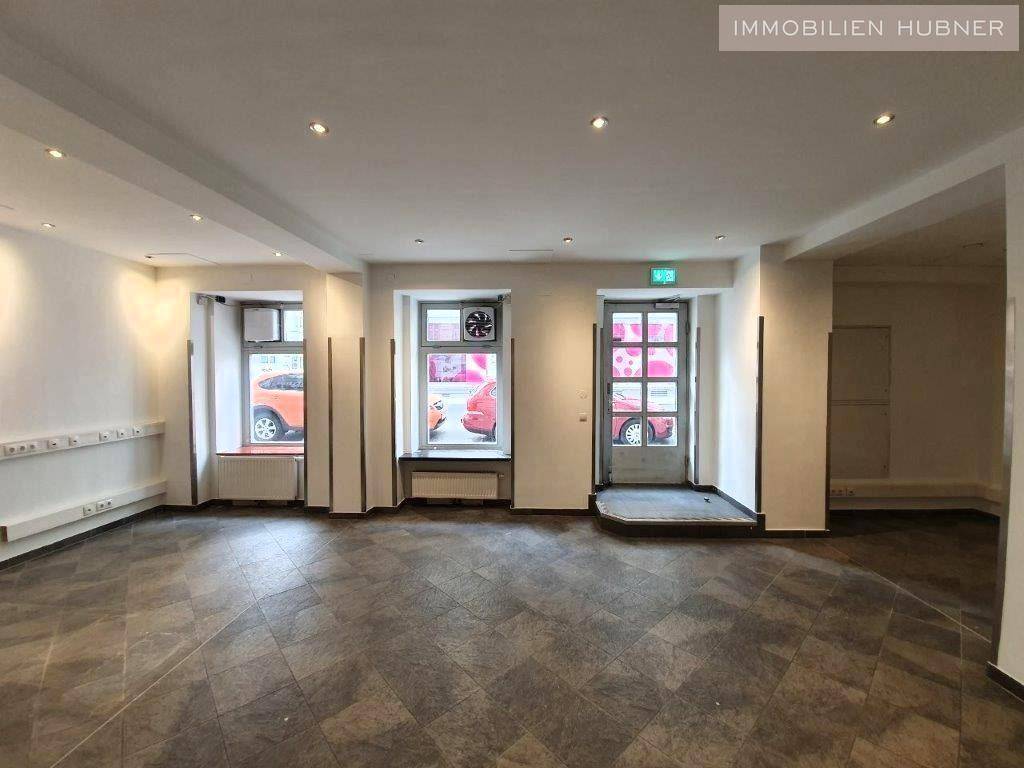 Gewerbefläche mit Eingangstür und großen Fenstern, die viel Tageslicht hereinlassen und zur Straße zeigen.