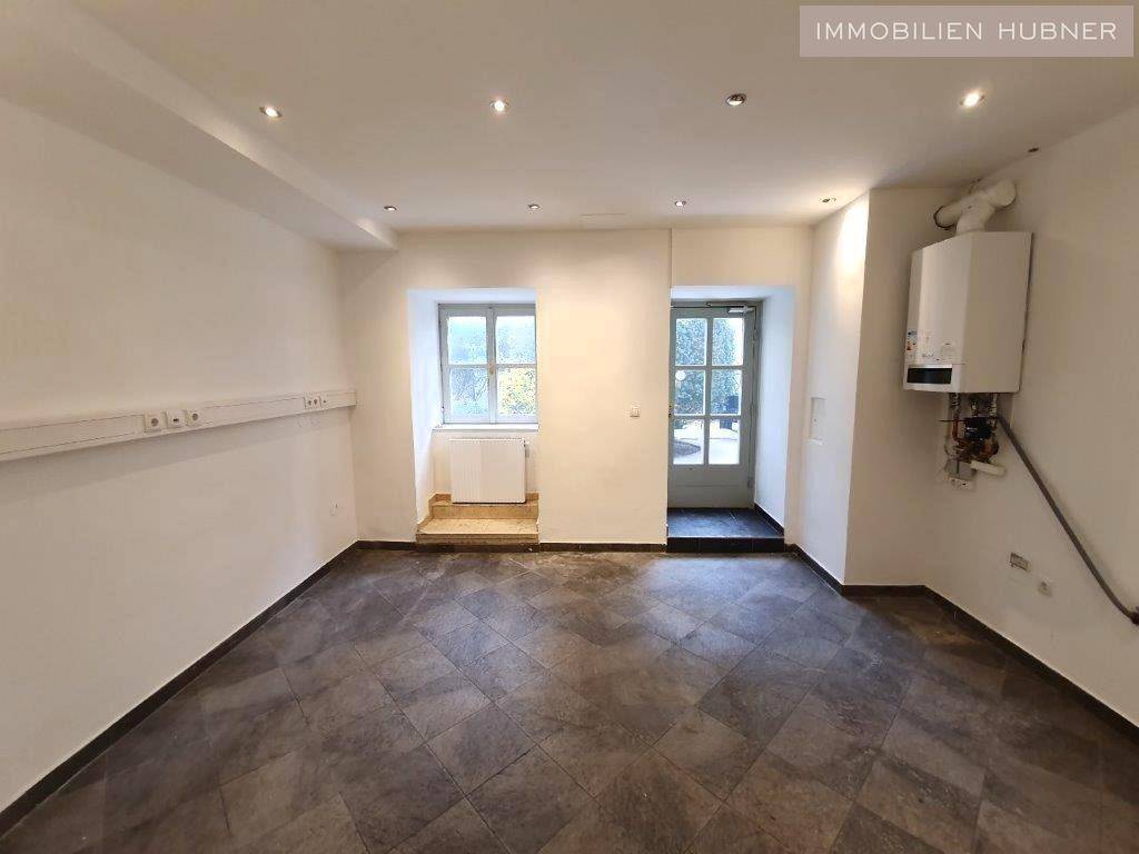 Kleinerer Raum mit Fenster, Außentür und einem an der Wand montierten Warmwasserbereiter.