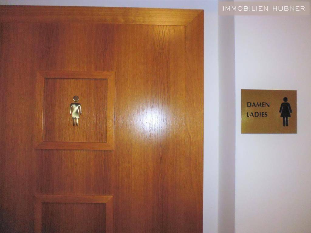 Holztür mit Beschilderung für die Damentoilette in deutscher und englischer Sprache.