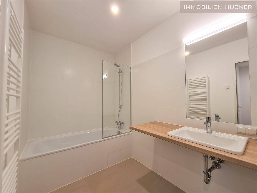 Modernes Badezimmer mit Badewanne, Duschabtrennung, Einzelwaschbecken und Handtuchheizkörper.
