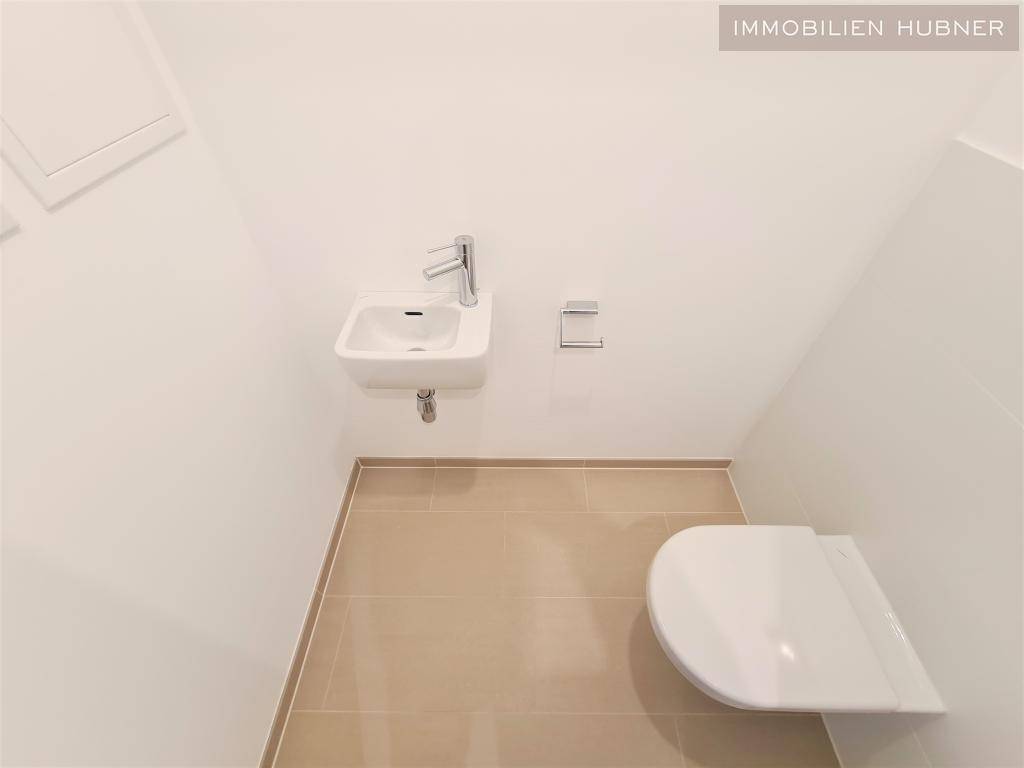 Separates Gäste-WC mit wandhängendem WC und kleinem Handwaschbecken.