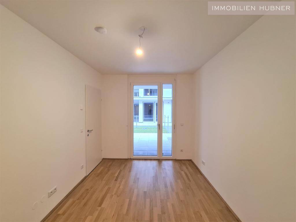Ruhiges Zimmer mit Parkettboden und Zugang zum Außenbereich, ideal als Schlaf- oder Arbeitszimmer.
