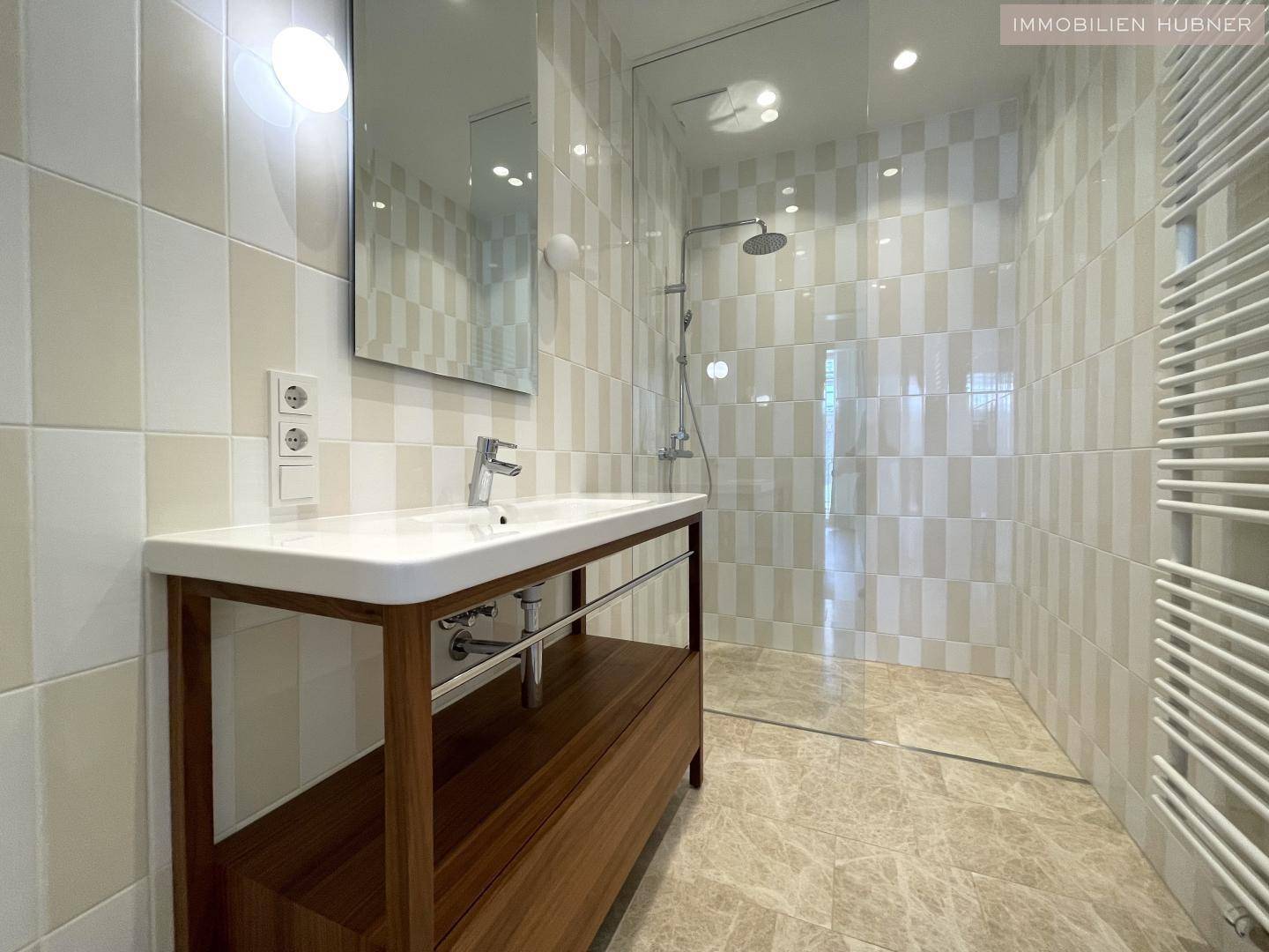 Modernes Badezimmer mit begehbarer Dusche, eleganten Fliesen und einem stilvollen Waschtisch.