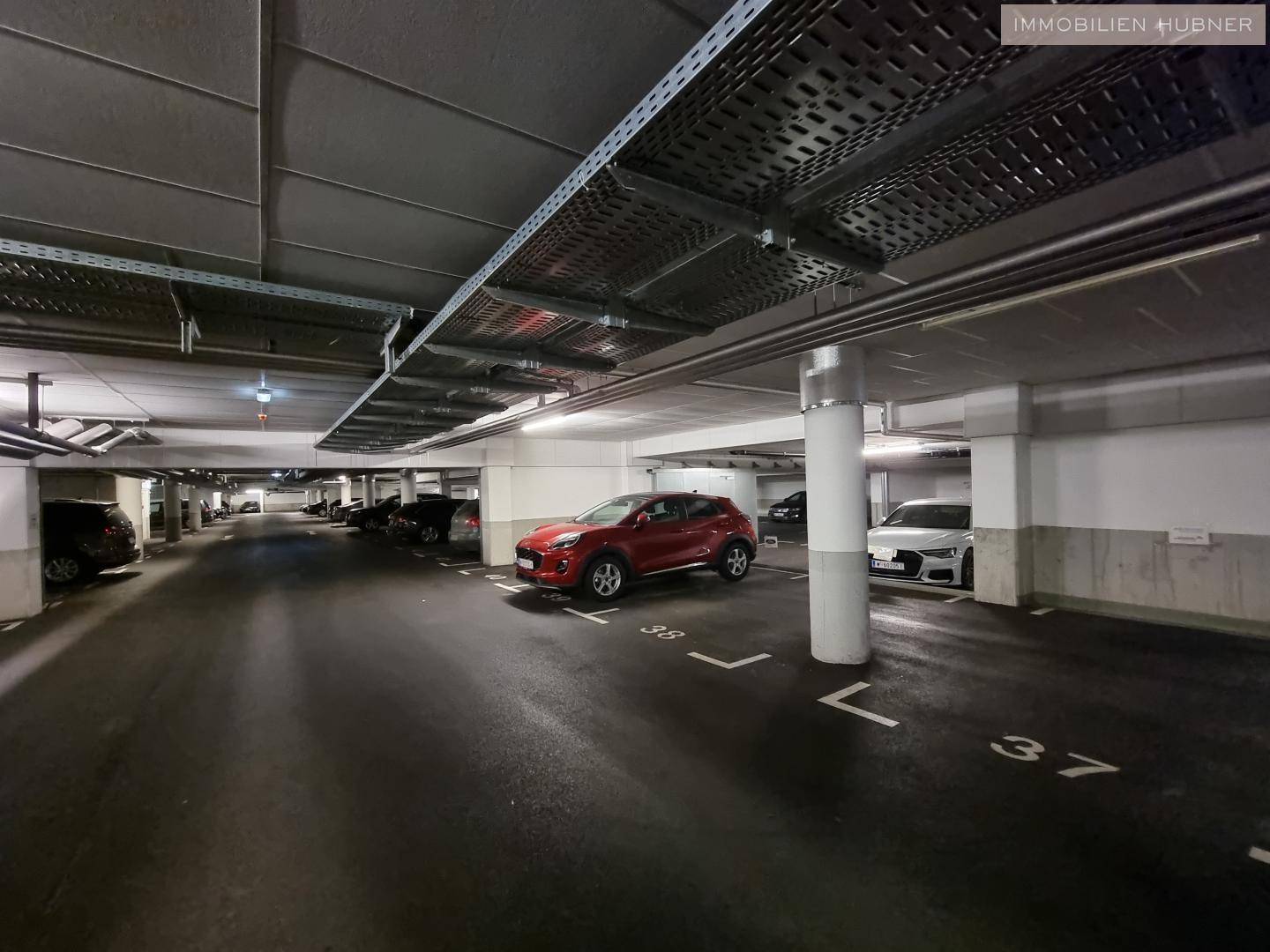 Tiefgarage mit zahlreichen Parkplätzen und geparkten Fahrzeugen.