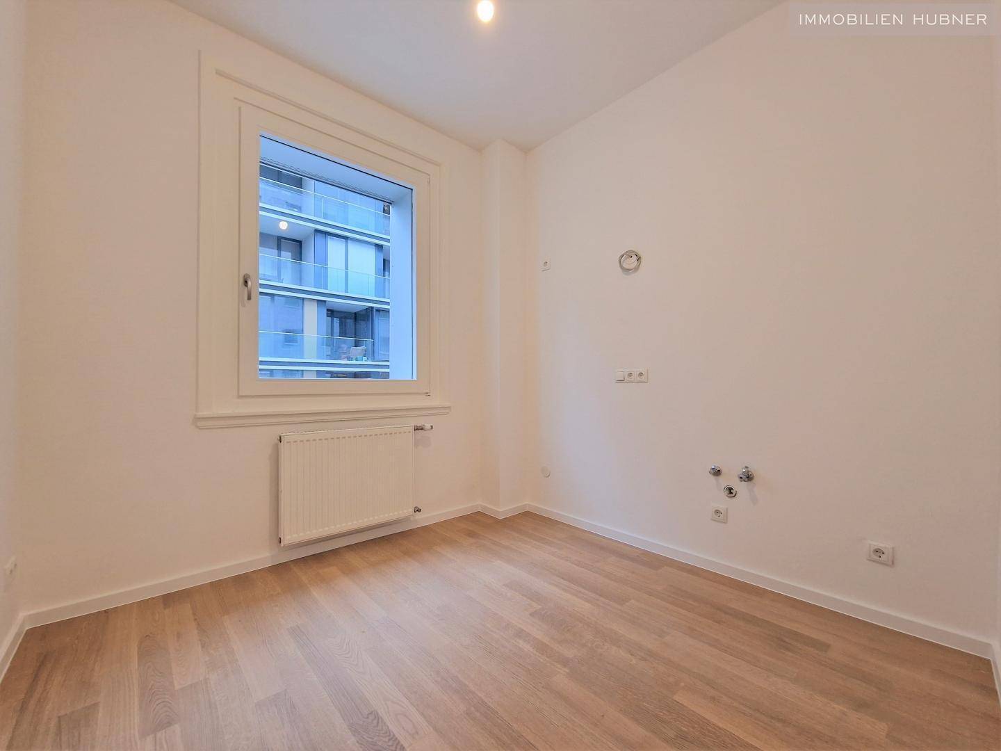Ruhiges Zimmer mit Holzboden, einem Fenster und Heizkörper, ideal als Schlaf- oder Arbeitszimmer.