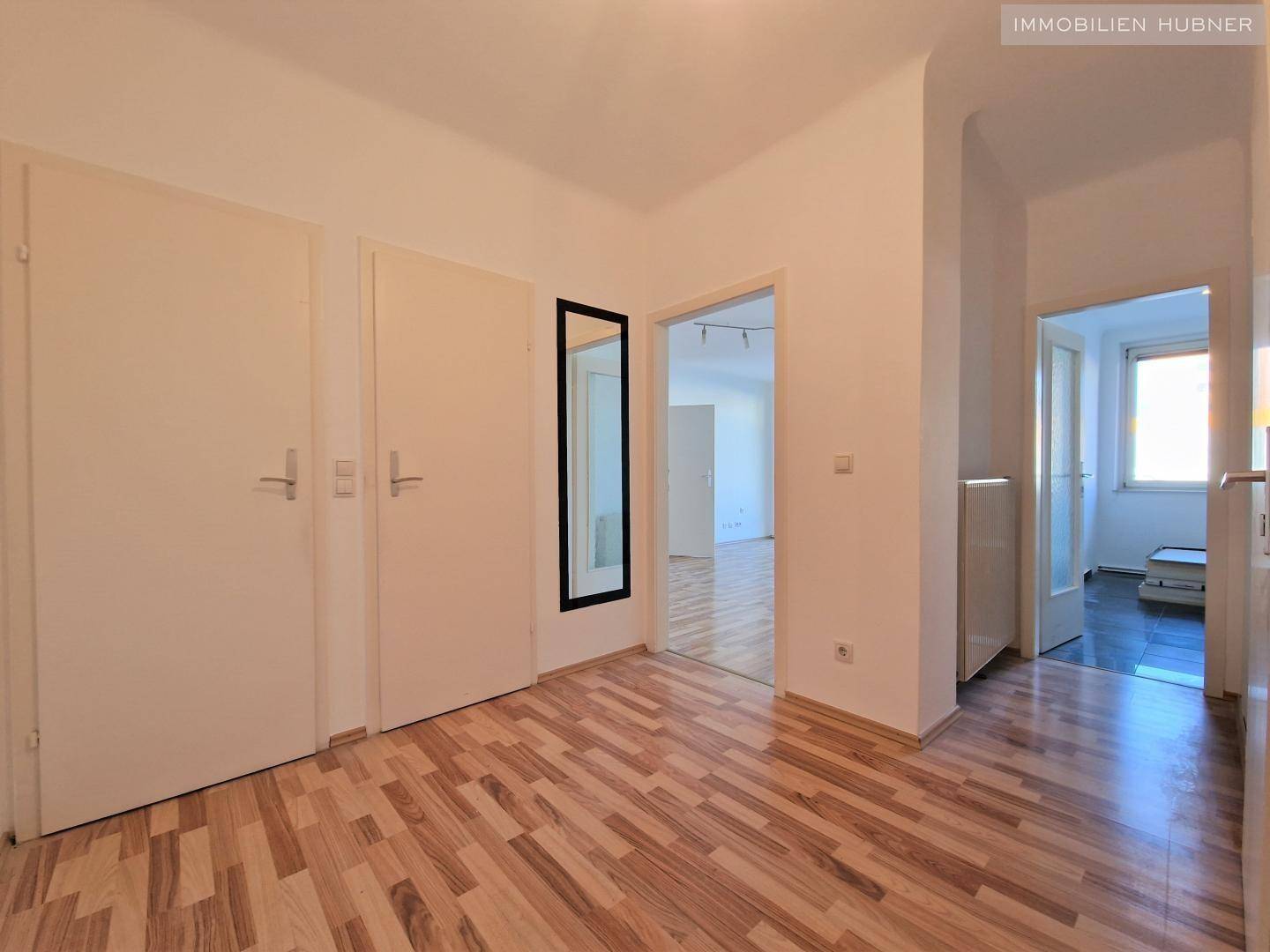 Heller Flur mit Laminatboden und mehreren Türen, der verschiedene Räume verbindet.
