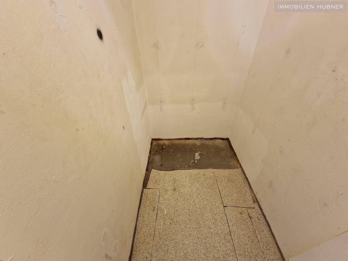 Kleiner Abstellraum mit einfachen Wänden und Boden, der renoviert werden muss.