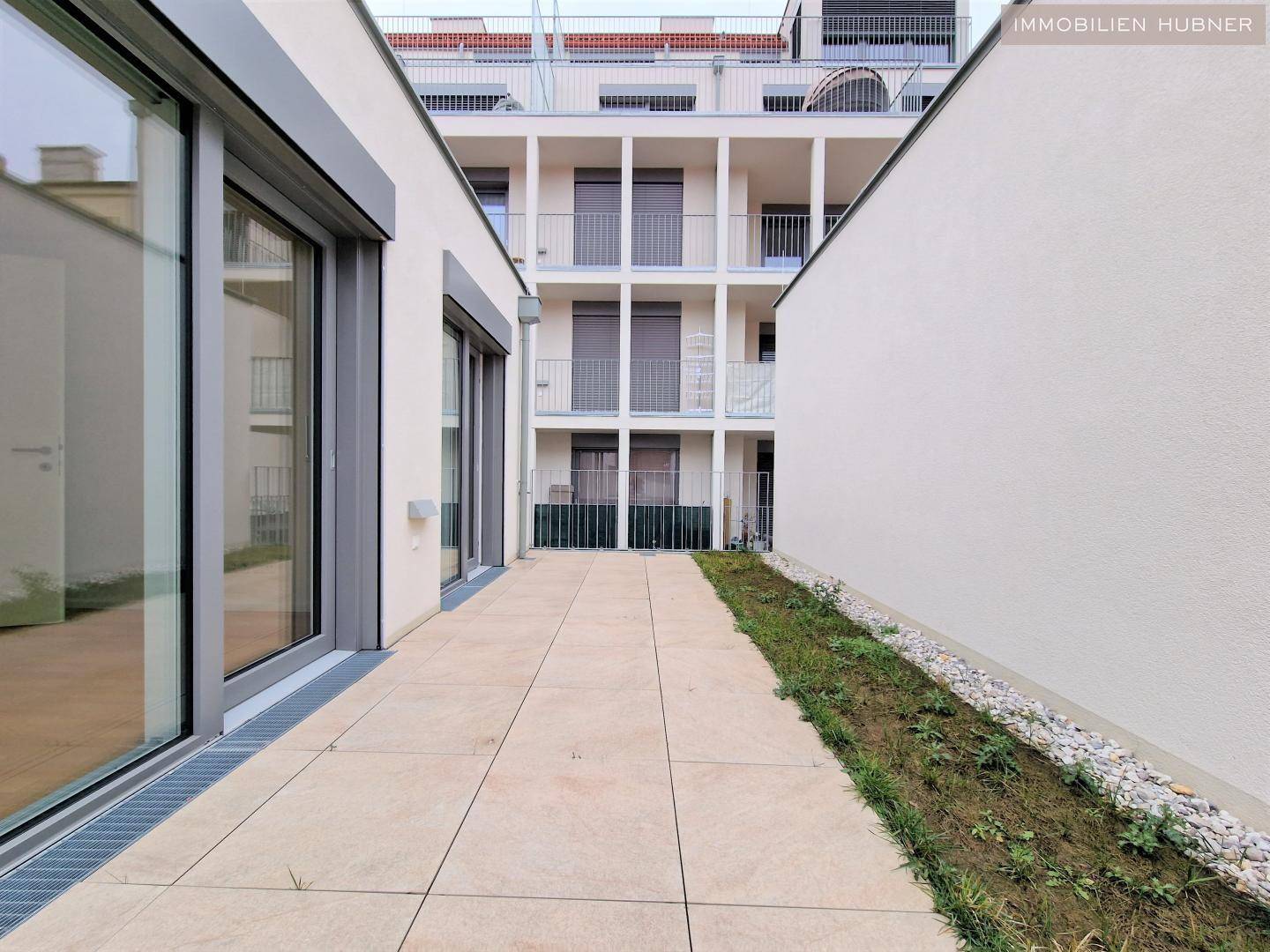 Außenbereich mit Terrasse und Blick auf die moderne Fassade des Wohngebäudes.