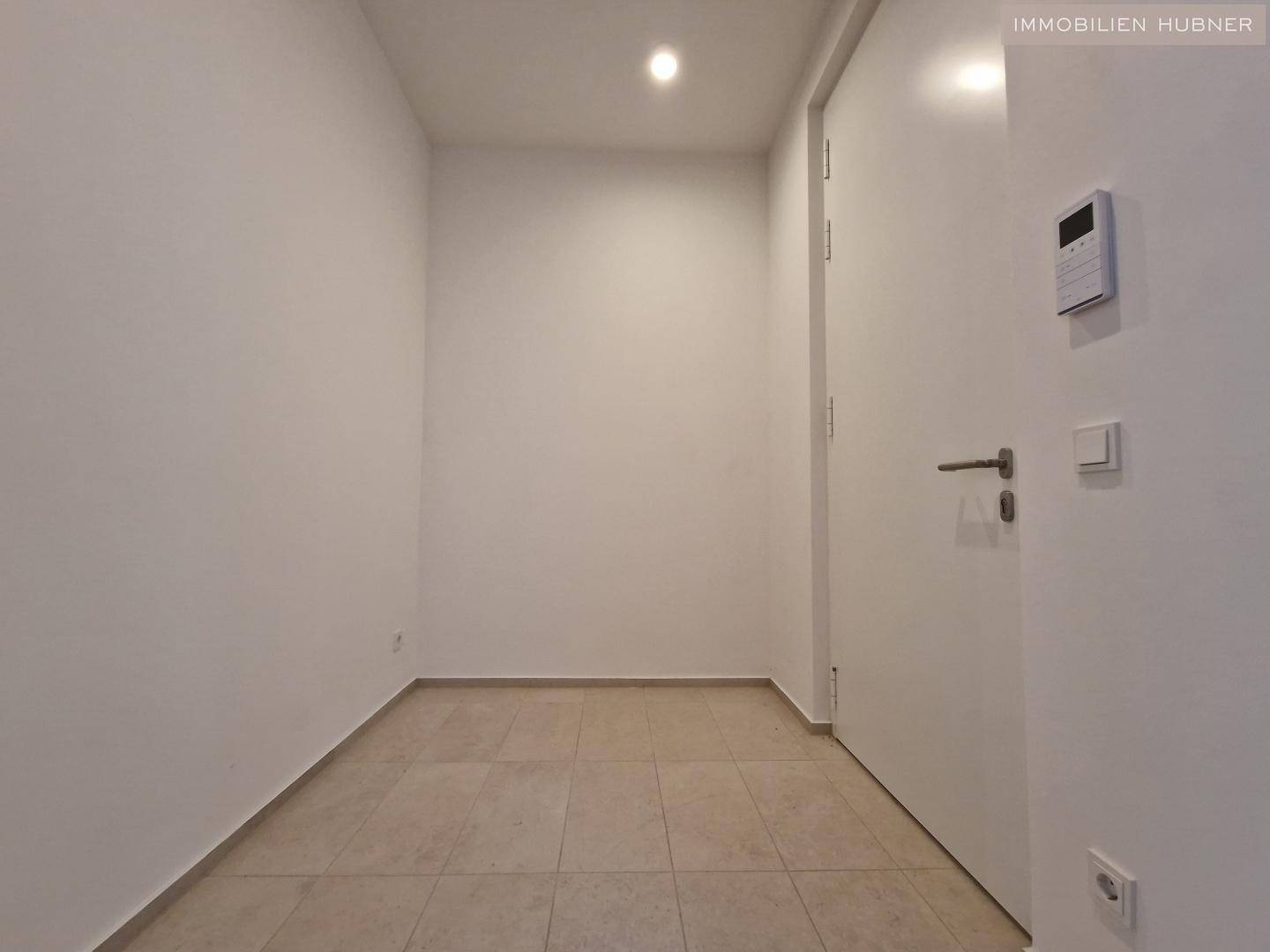 Heller Eingangsbereich mit Fliesenboden und weißer Tür, modern und funktional gestaltet.