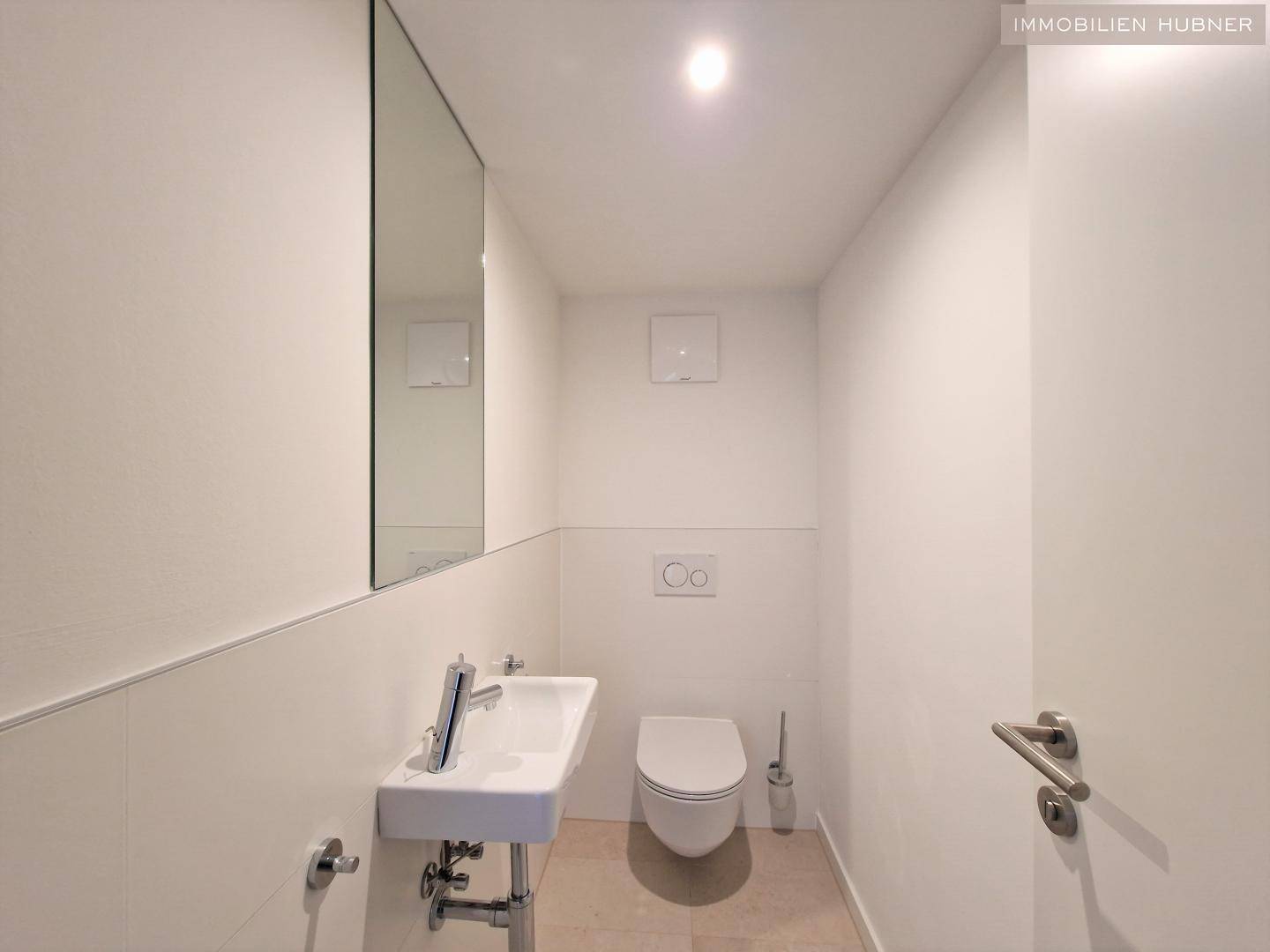 Modernes Gäste-WC mit wandhängendem WC, kleinem Waschbecken und Spiegel.
