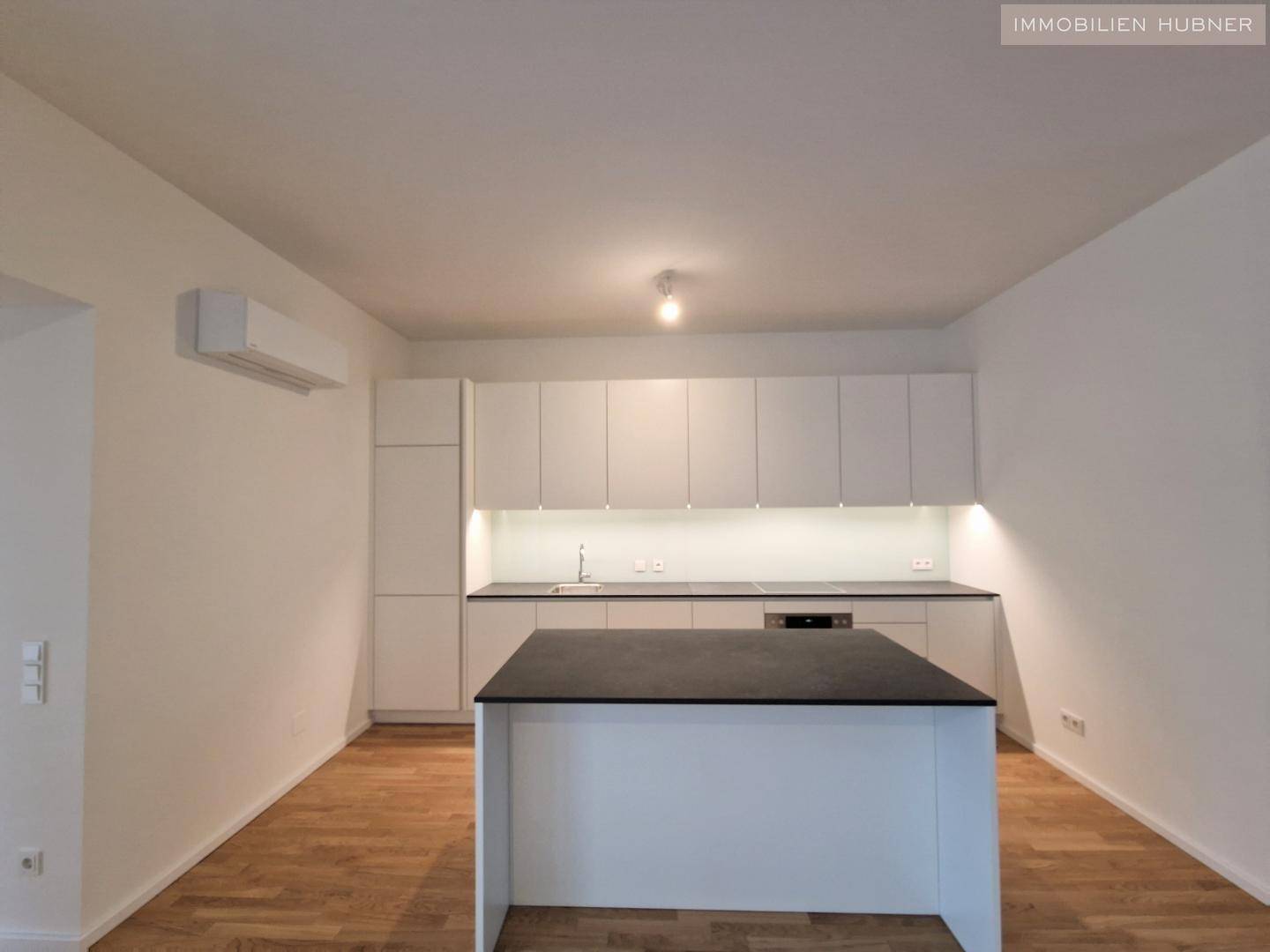 Helle, minimalistische Küche mit Kochinsel und modernen weißen Schränken in neuwertigem Zustand.