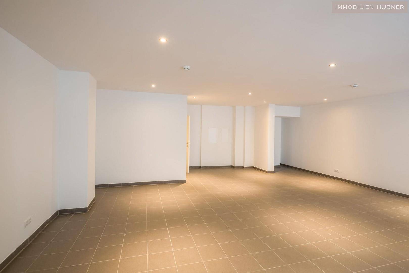 Geräumiger, leerer Geschäftsraum mit hellen Fliesen und Einbaustrahlern in der Decke, bereit zur Gestaltung.