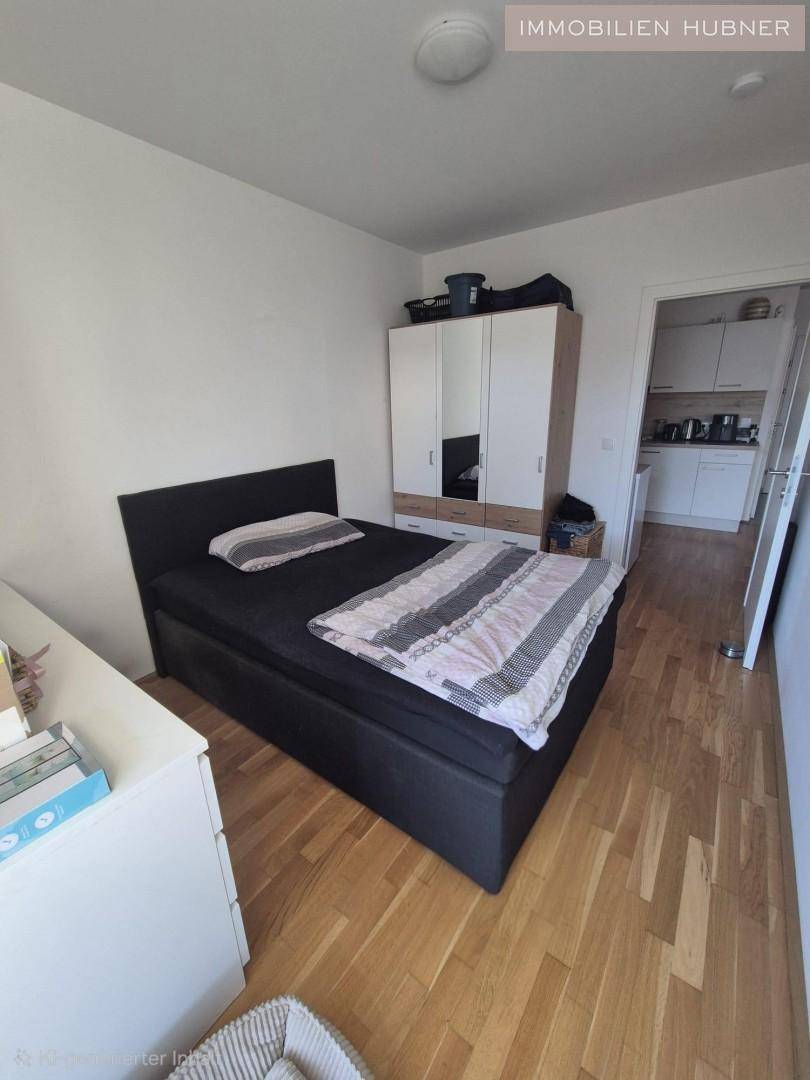 Gemütliches Schlafzimmer mit Holzboden, Doppelbett und Kleiderschrank, mit Zugang zur Küche.