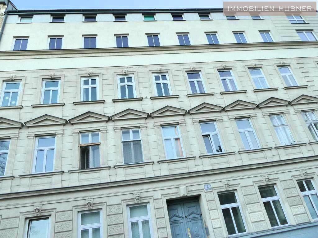 Klassische Fassade eines Mehrfamilienhauses mit vielen Fenstern und dekorativen Elementen.
