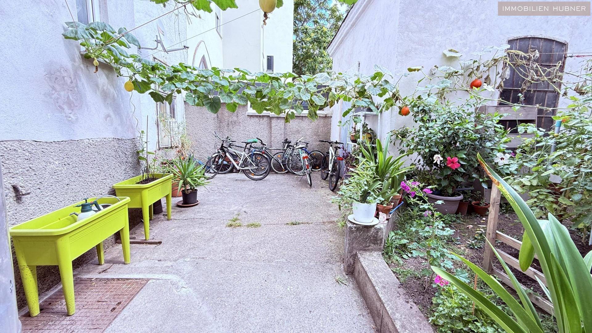 Begrünter Innenhof mit Fahrrädern und Pflanzen, der als Gemeinschaftsbereich dient.