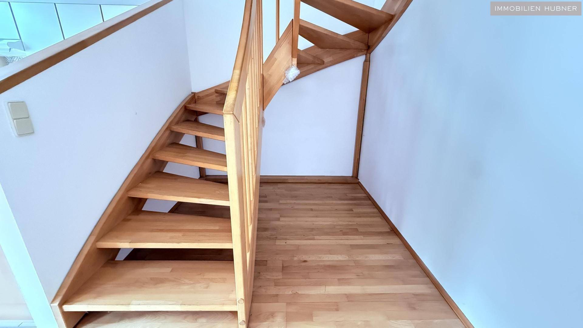 Robuste Holztreppe mit Geländer, die die beiden Ebenen der Wohnung miteinander verbindet.
