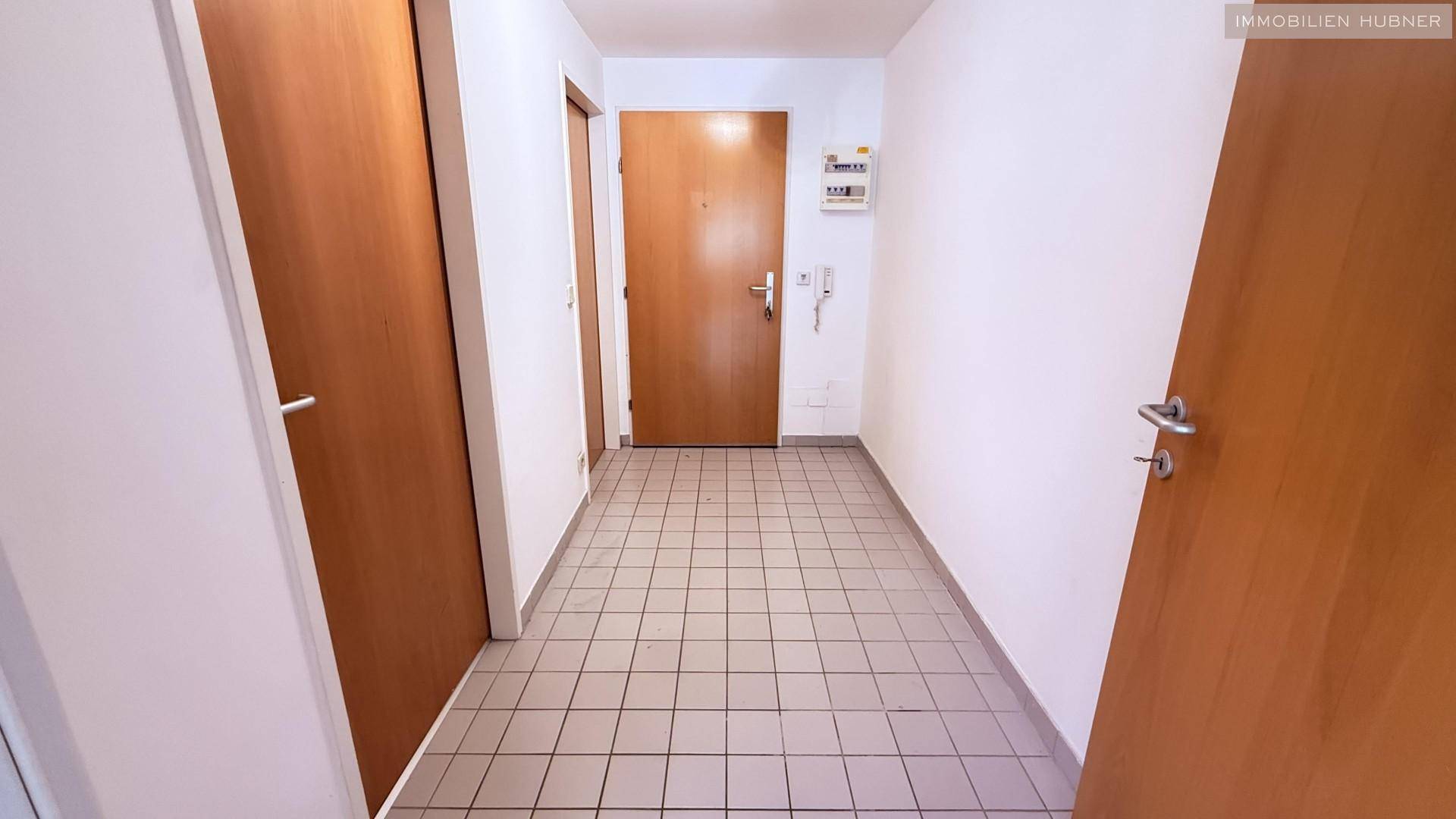 Langer Flur mit Fliesenboden und mehreren Holztüren, die zu verschiedenen Räumen führen.