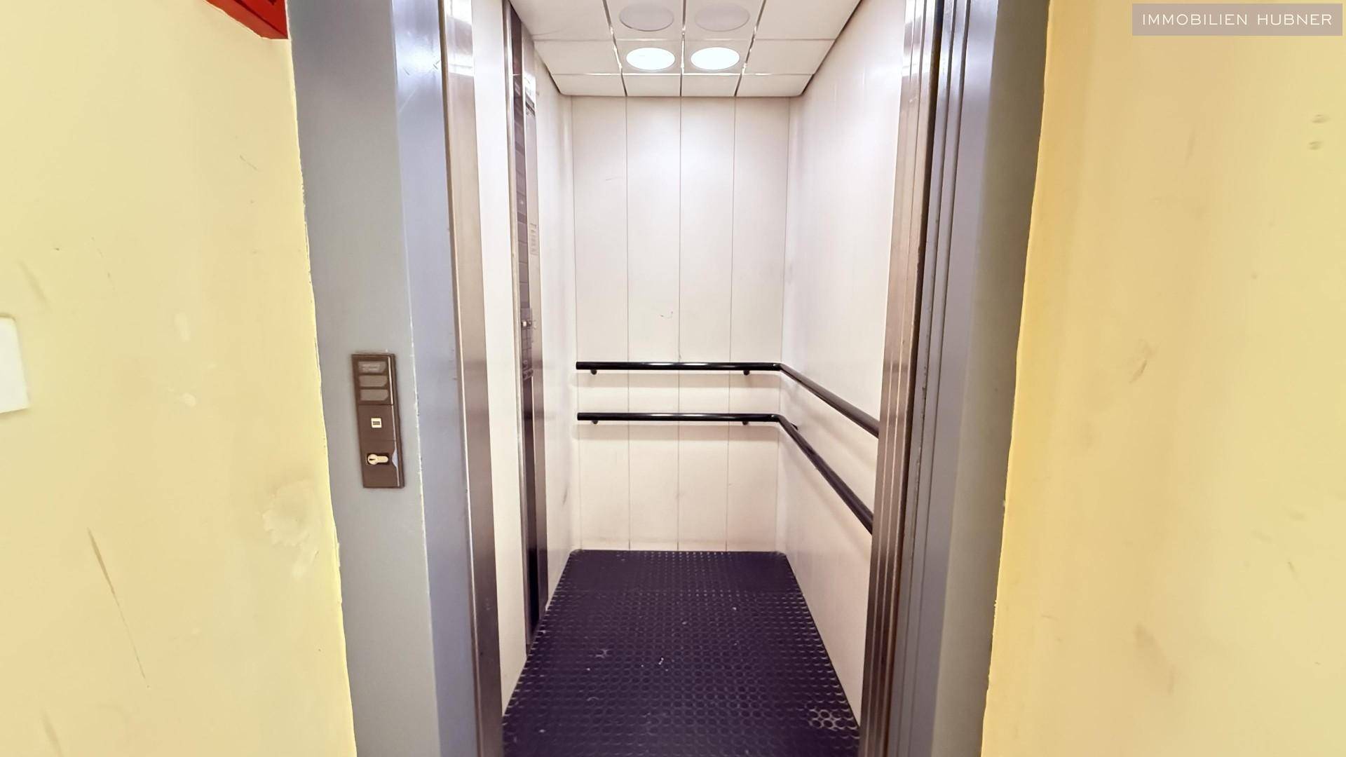 Innenansicht eines Aufzugs mit Metalltüren und Haltegriffen für Barrierefreiheit.