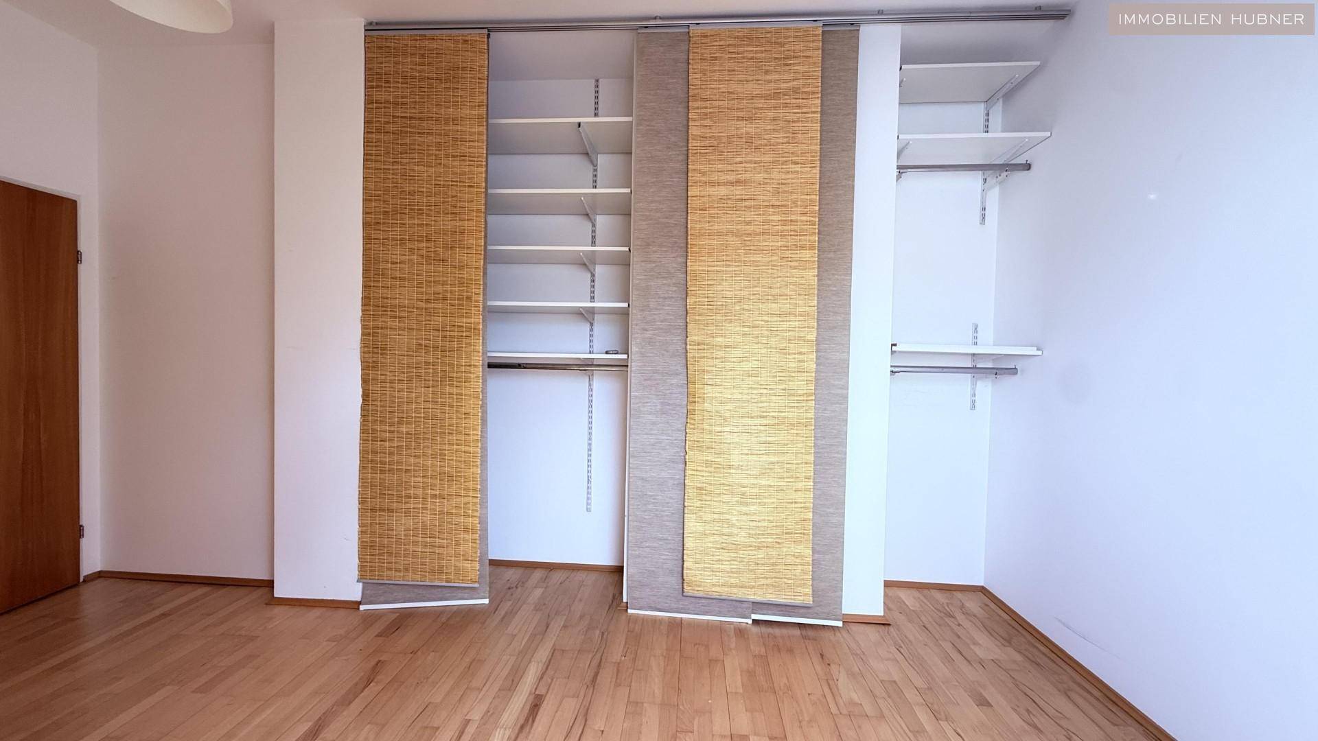 Schlafzimmer mit Holzboden und integriertem Schranksystem mit Schiebetüren.