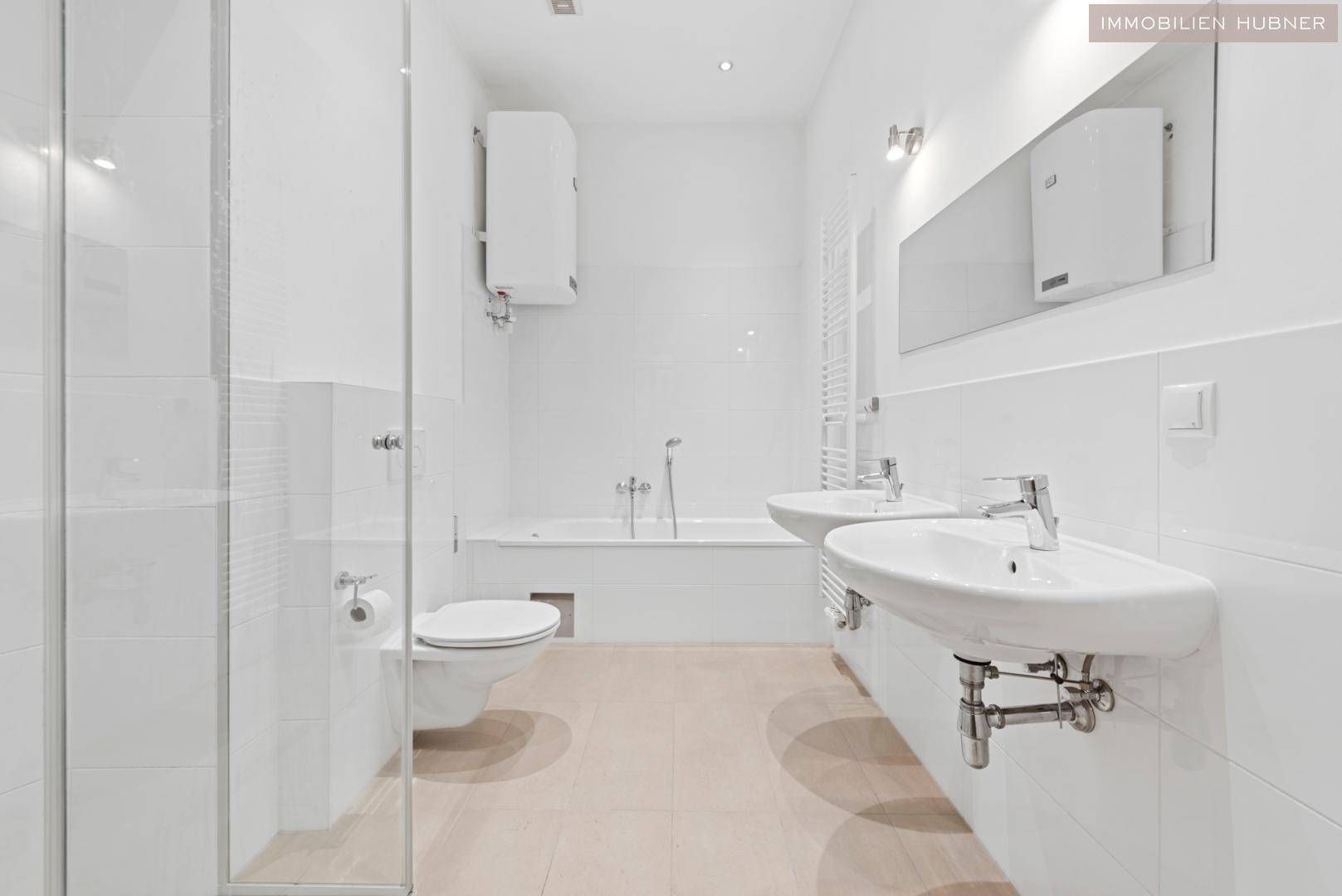 Modernes Badezimmer mit weißen Fliesen, Doppelwaschbecken, Badewanne und Duschkabine.