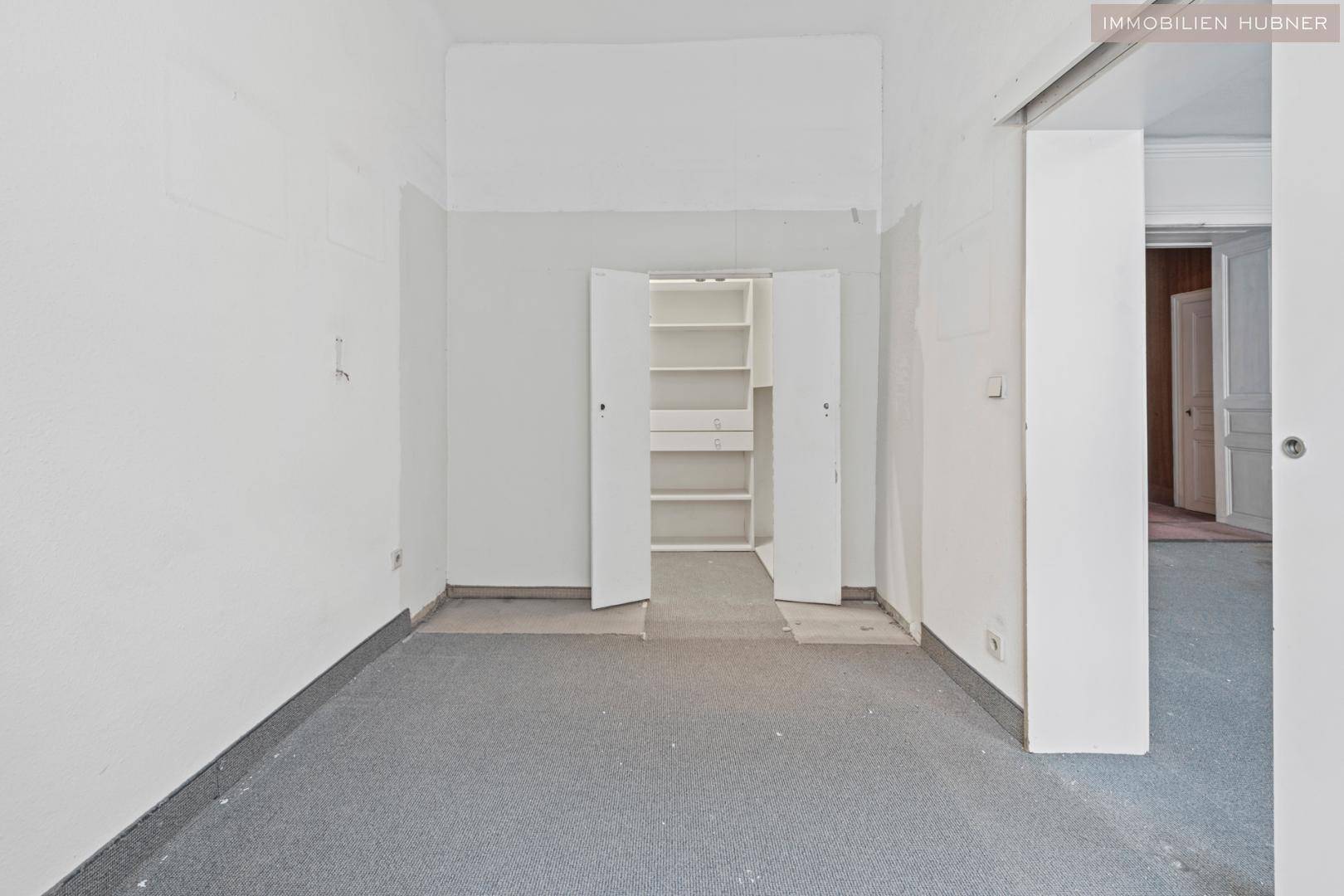 Renovierungsbedürftiger Raum mit eingebautem Schrank und Teppichboden, ideal als Schlafzimmer.