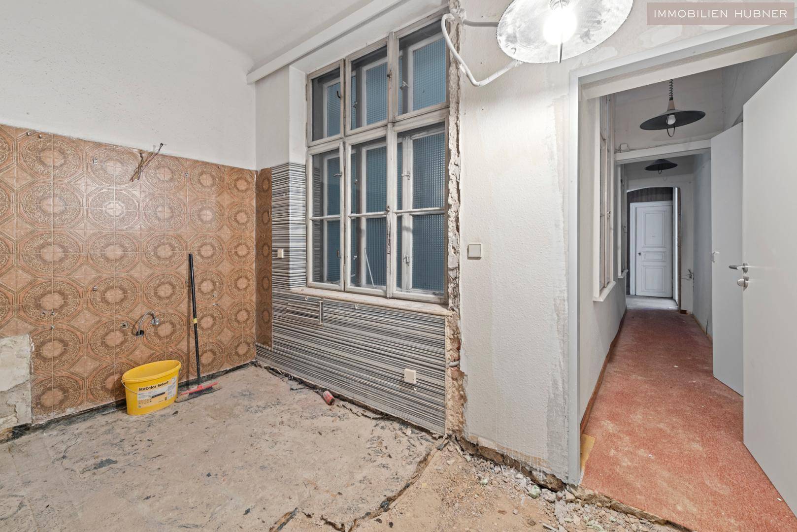 Küche in Renovierung mit alten Fliesen und Fenster, bereit für eine moderne Neugestaltung.