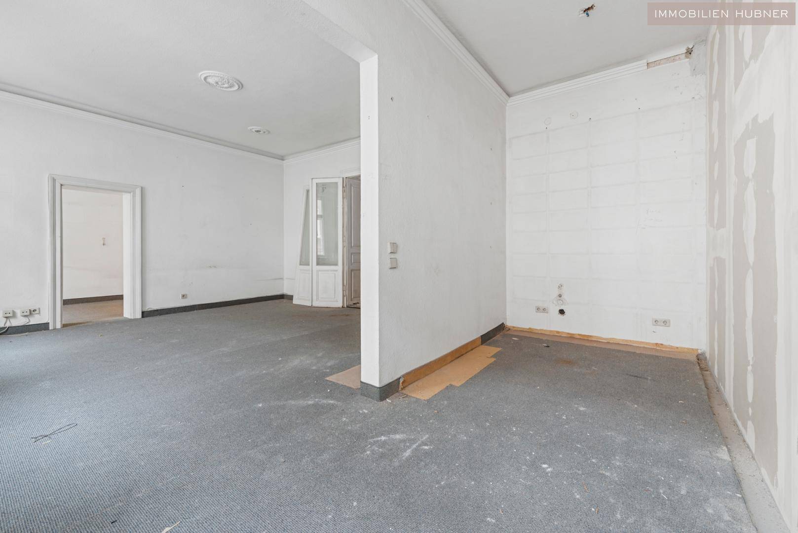 Geräumiger Raum in Renovierung mit Teppichboden und vorbereiteten Wänden für den Ausbau.