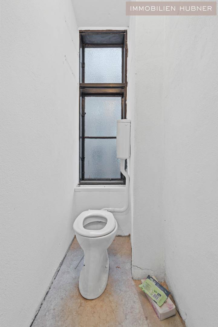 Kleines WC mit Fenster und einfacher Toilette in sanierungsbedürftigem Zustand.