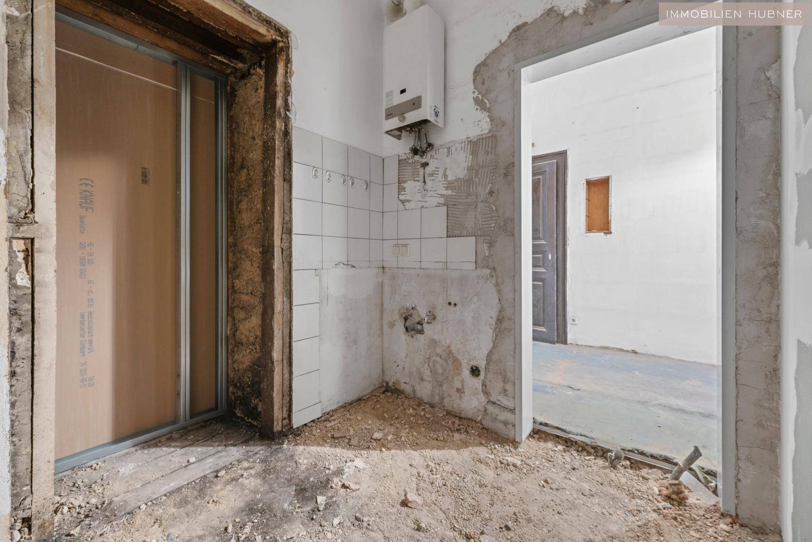 Sanierungsbedürftige Küche oder Hauswirtschaftsraum mit Wandfliesen und Warmwasserbereiter.
