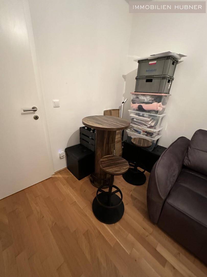 Kleiner Bartisch mit Hockern und Stauraum neben einem Sofa in einem Innenraum.