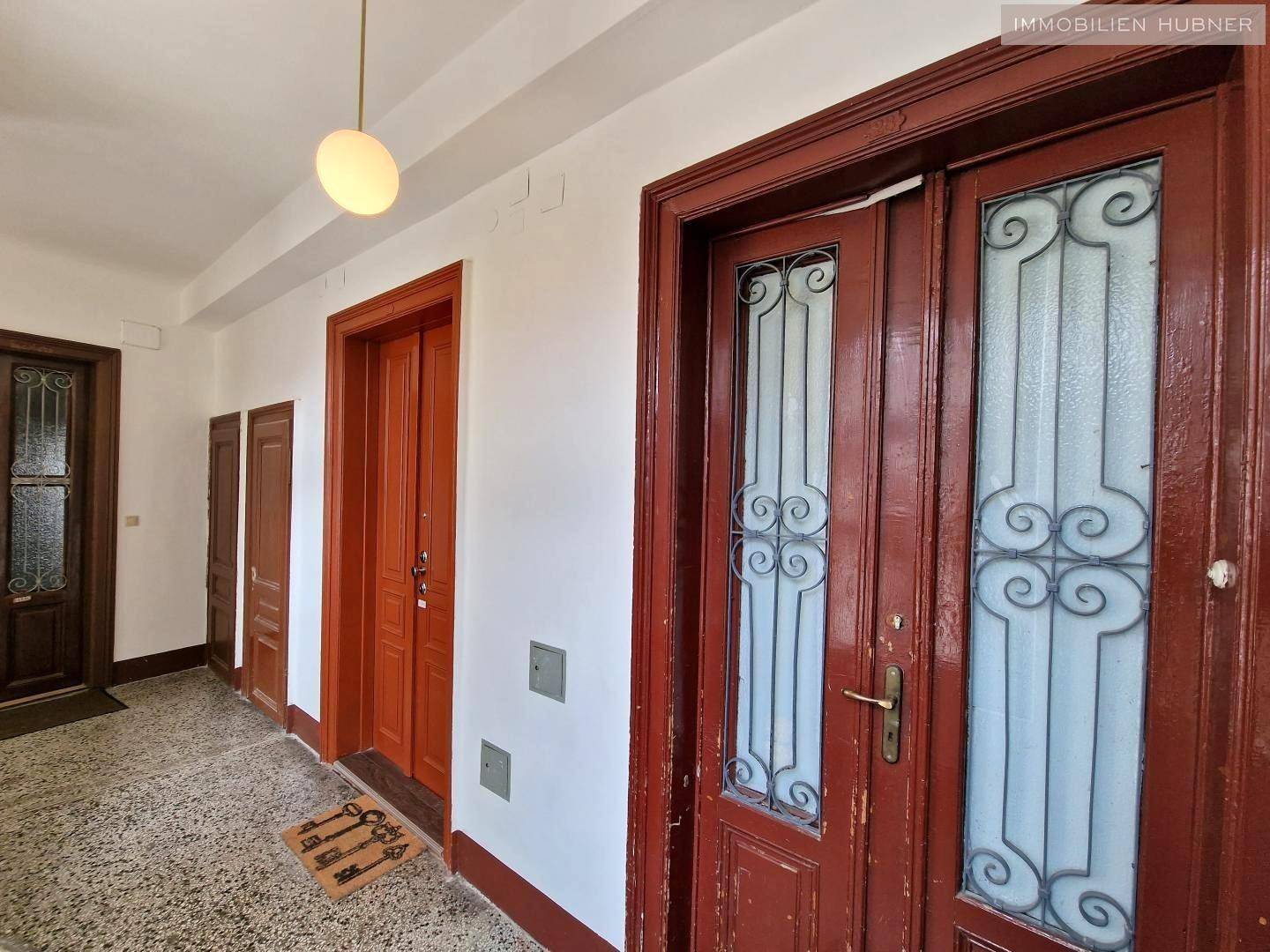 Historischer Flur mit verzierten Holztüren und Terrazzoboden in einem Altbau.