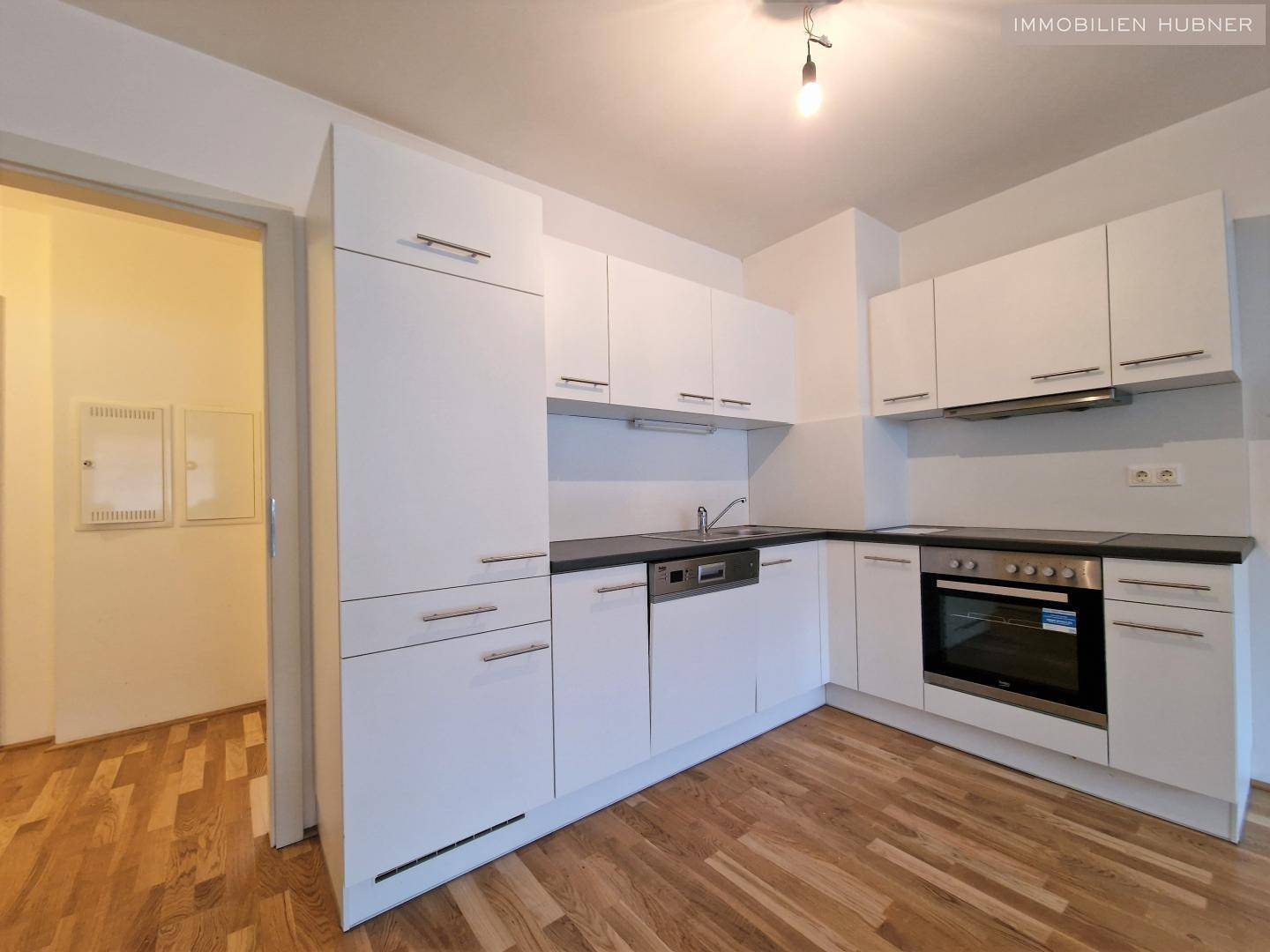 Moderne Einbauküche in Weiß mit dunkler Arbeitsplatte und integrierten Geräten.